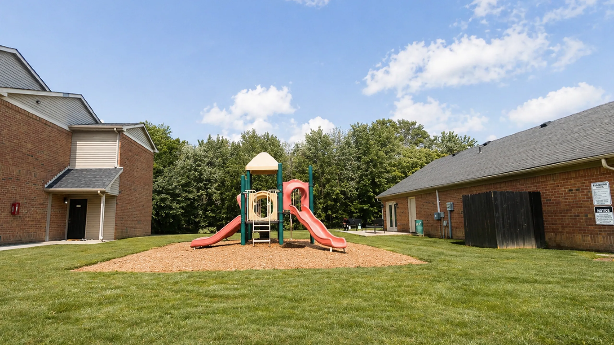 Charming residential area with a vibrant playground surrounded by lush green grass, ideal for family-friendly living.