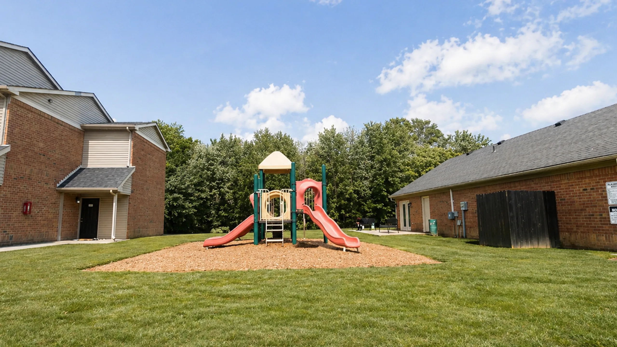 Charming community playground set amidst lush green lawns, perfect for family fun in a residential neighborhood.