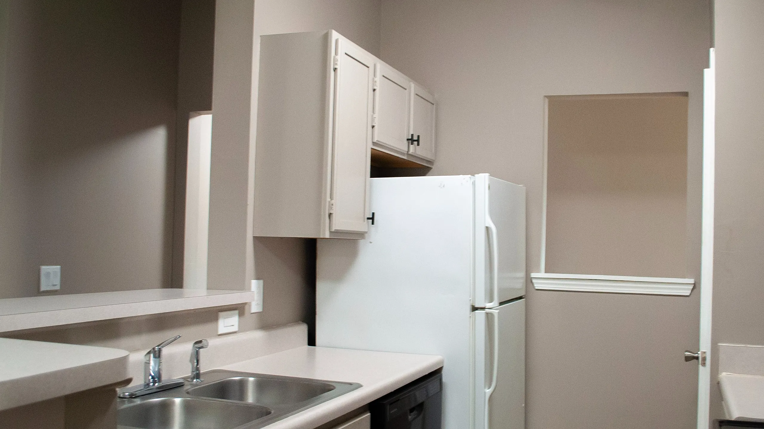 Modern kitchen with sleek countertops, double sink, and ample cabinetry, perfect for culinary enthusiasts.