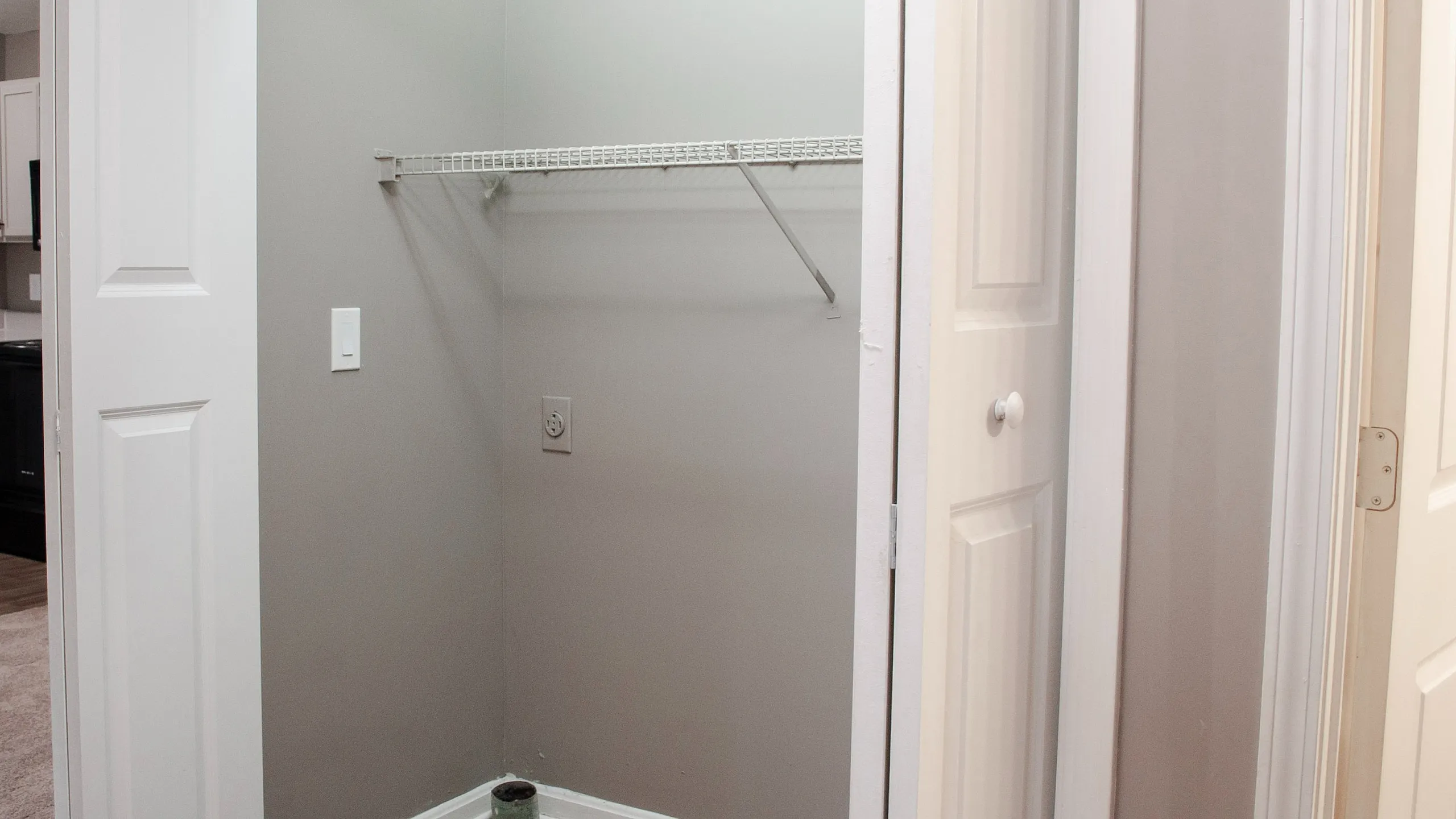 Charming apartment walk-in closet with sleek shelving, modern paint, and seamless access to a tidy kitchen area.