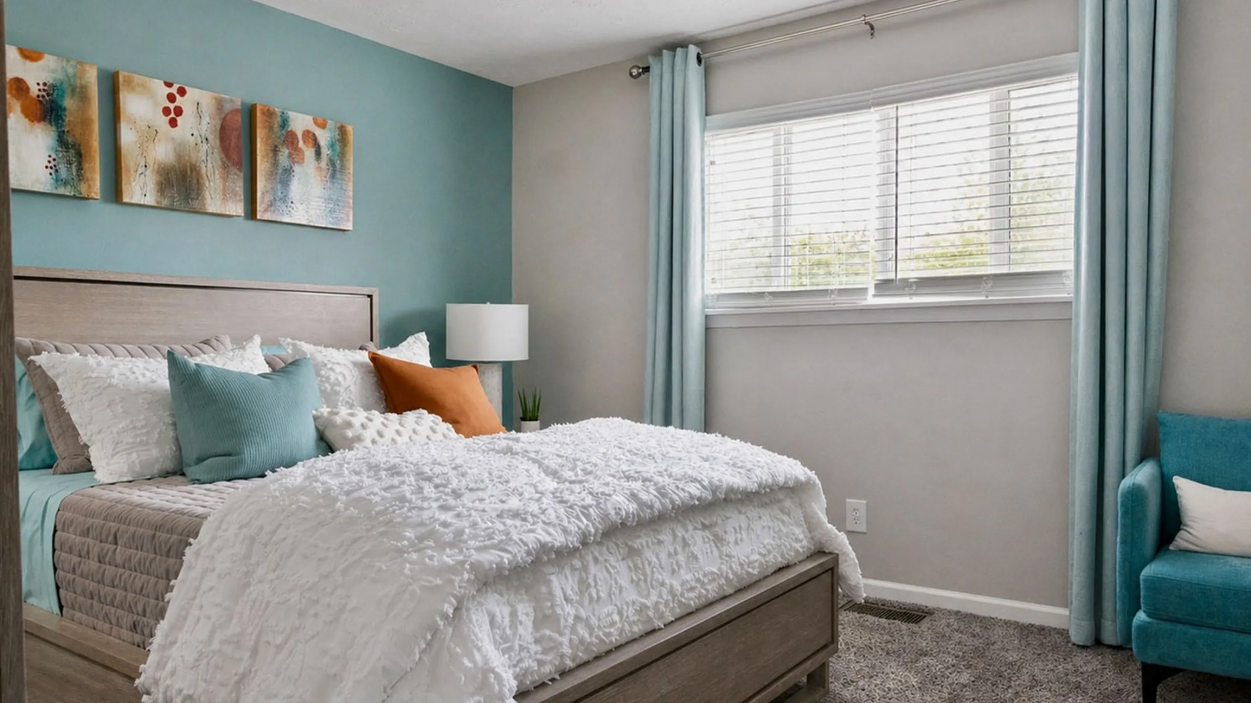 Charming bedroom with a modern design featuring a plush bed, colorful cushions, and soothing blue accents, bathed in natural light.