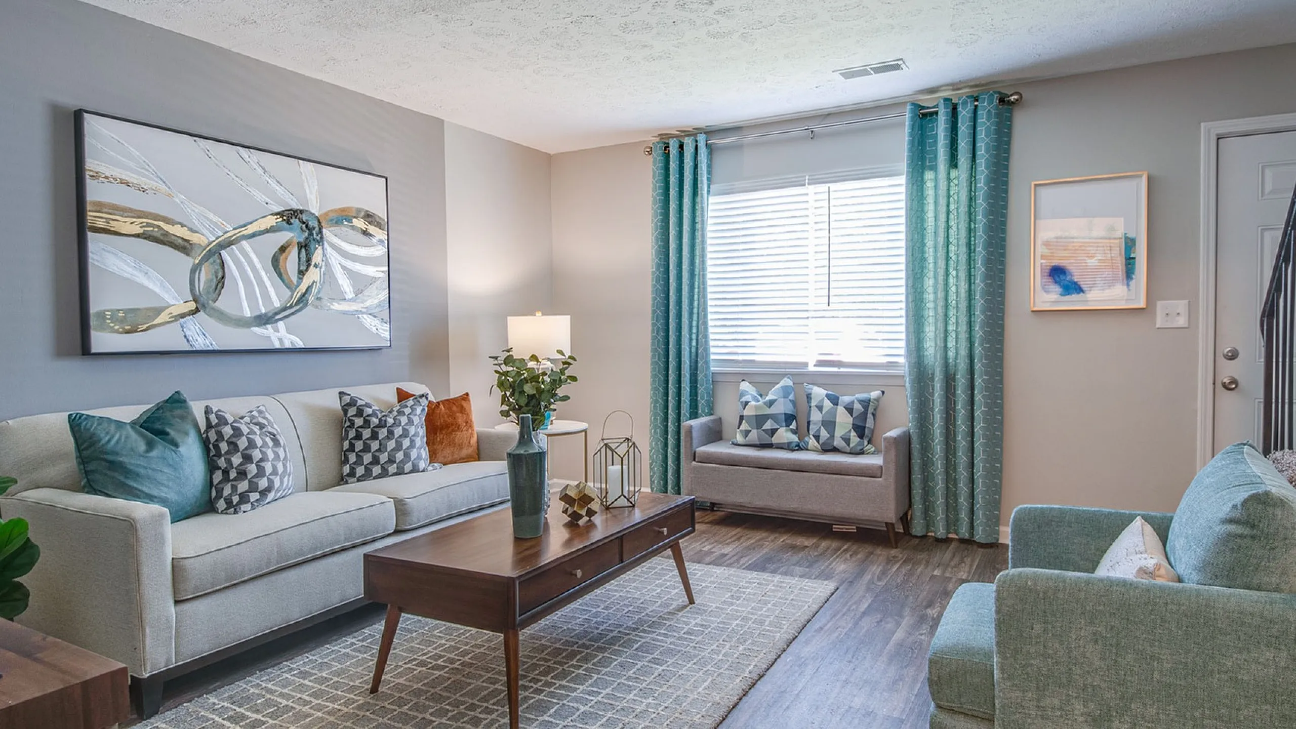 Charming living room with modern decor, featuring a cozy sofa, stylish accents, and vibrant teal curtains inviting natural light.