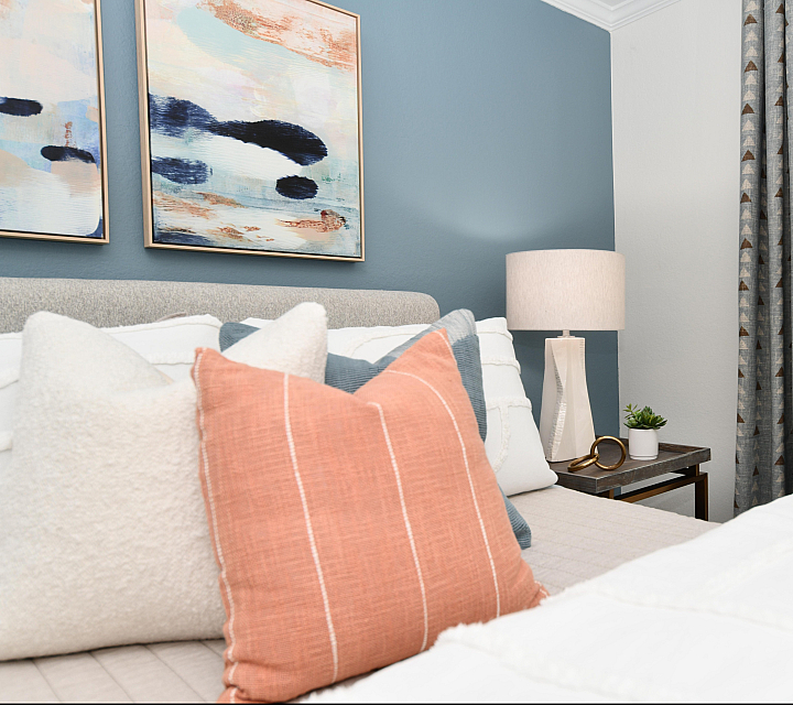 Inviting bedroom with cozy cushions, elegant wall art, and natural light through large windows.