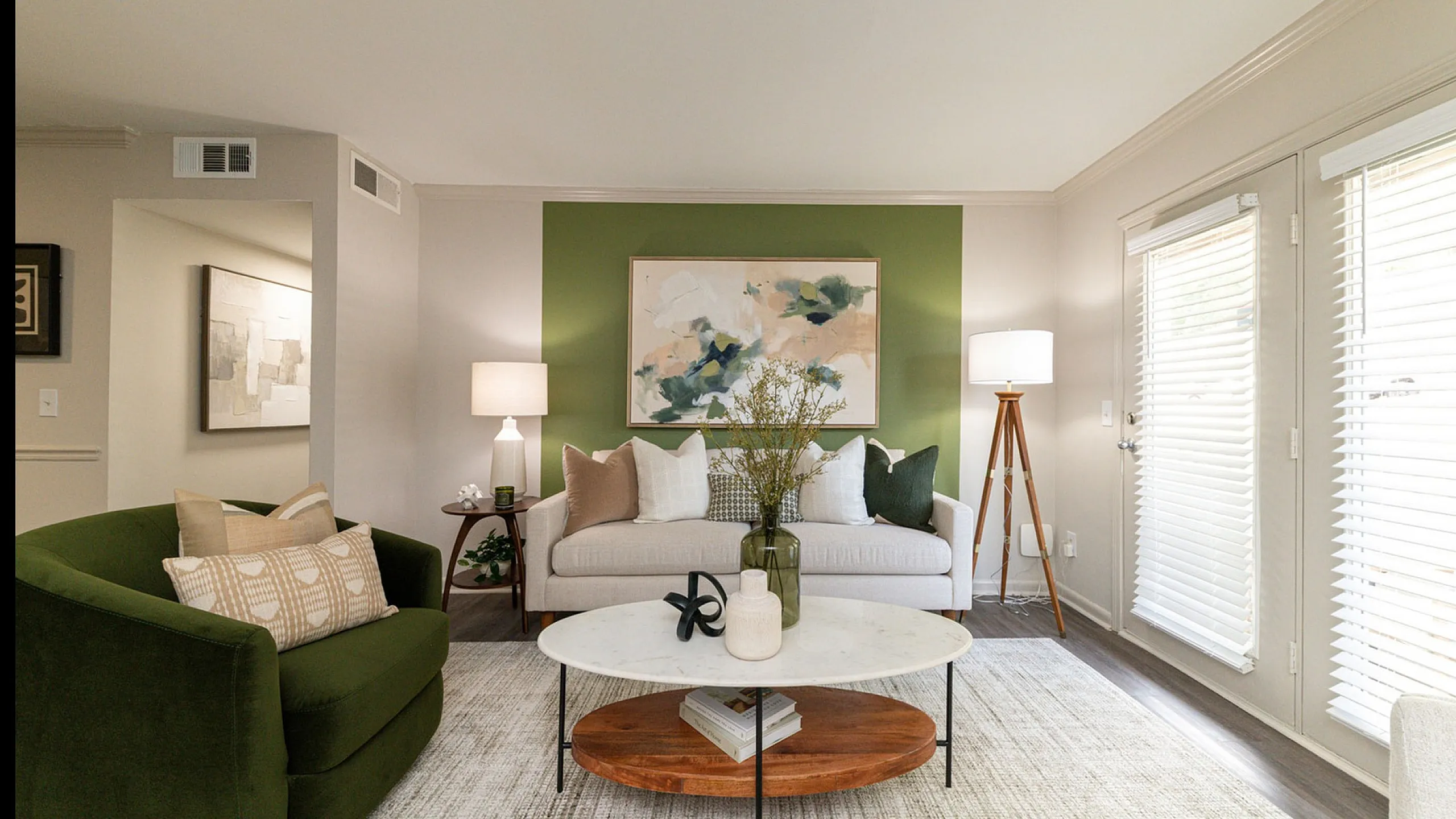 Inviting living room with modern decor, featuring a cozy green armchair, stylish sofa, and vibrant wall art in a sunlit ambiance.