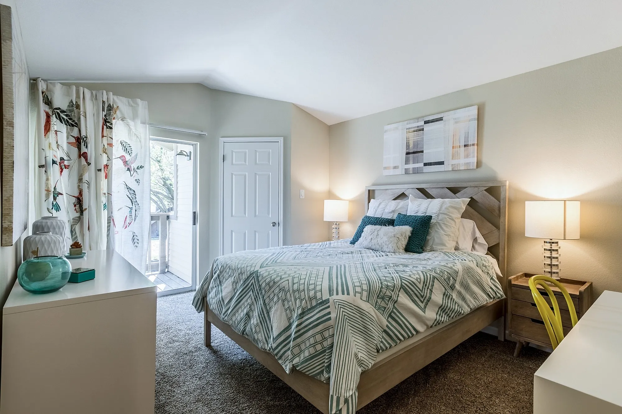 Bright and cozy bedroom featuring stylish decor, plush carpeting, and natural light pouring through elegant, patterned curtains.