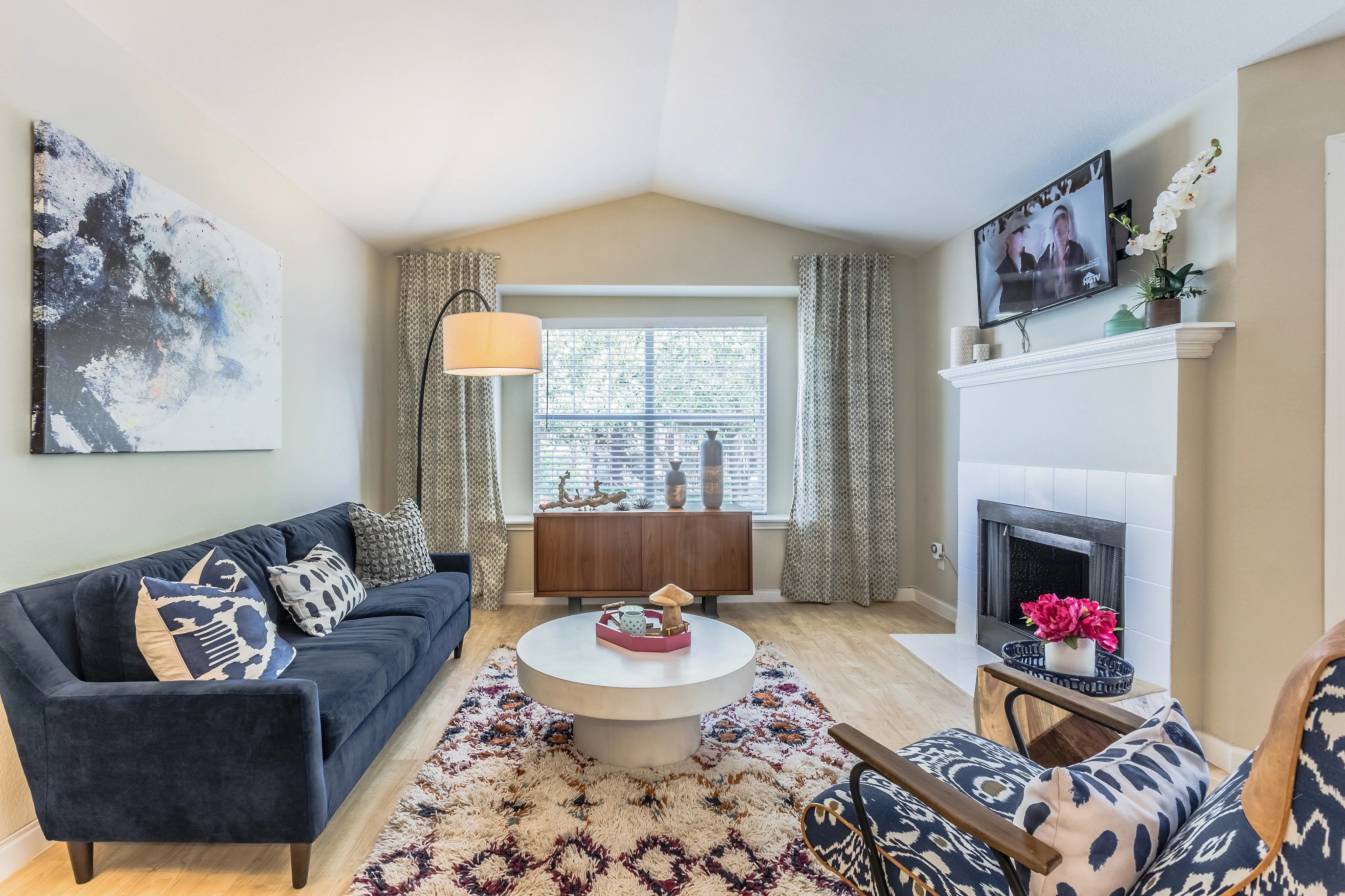 Inviting living room featuring a plush navy sofa, stylish armchair, and elegant fireplace, highlighted by a contemporary art piece and vibrant decor.