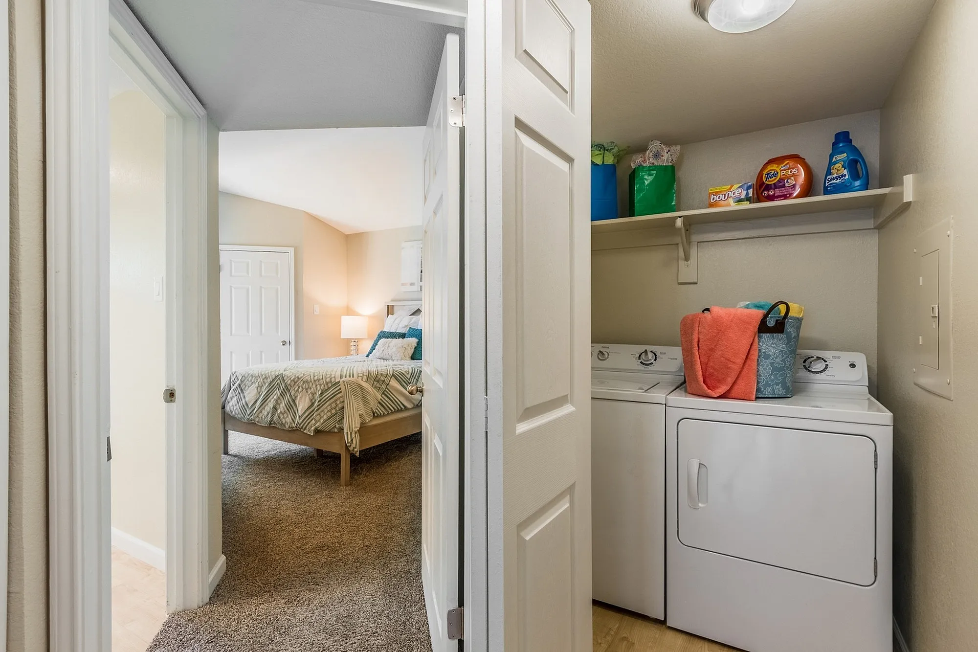 Inviting apartment interior featuring a cozy bedroom with soft lighting and a conveniently located laundry area equipped with modern appliances.