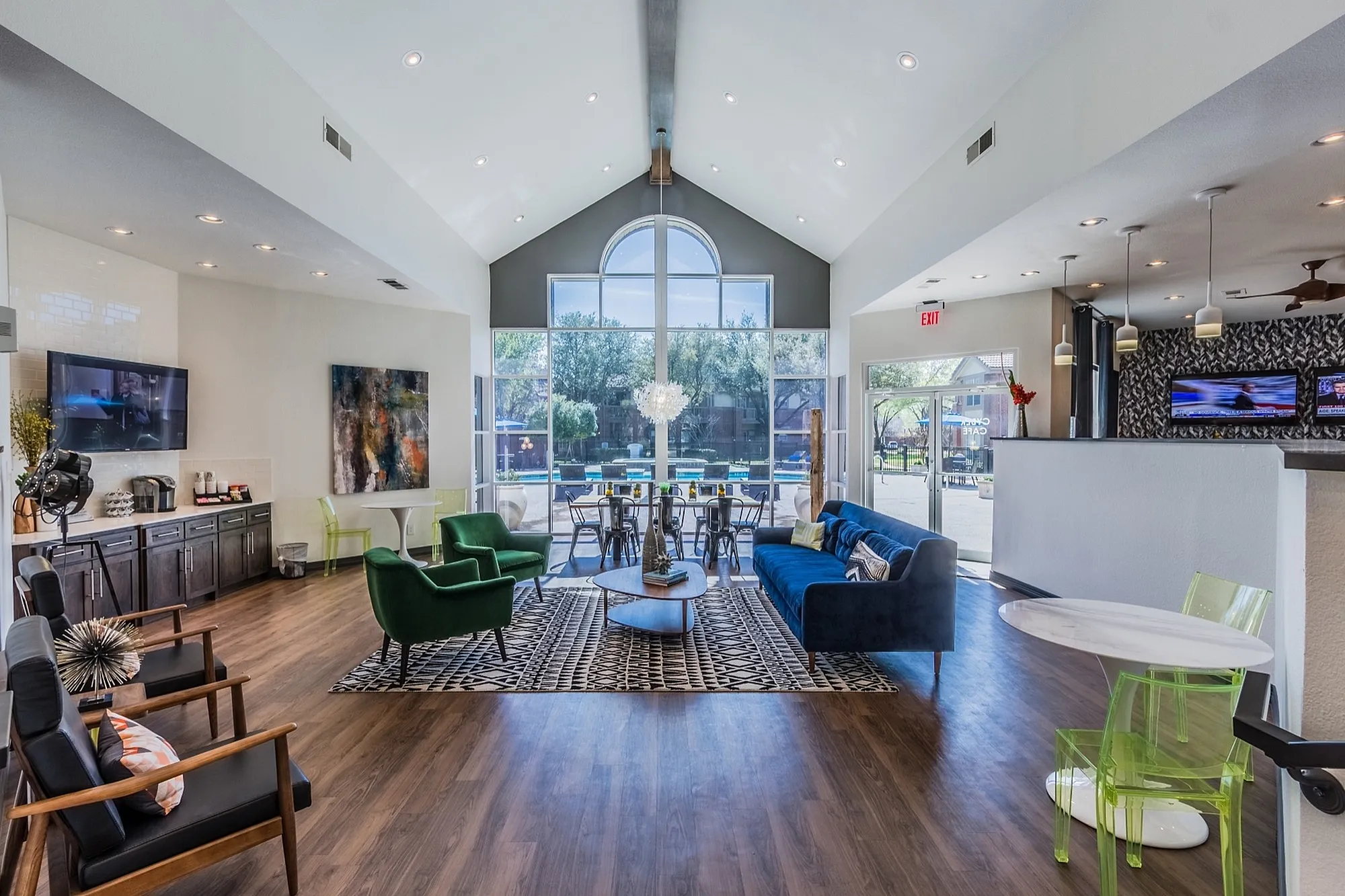 Elegant and spacious lounge area featuring modern furniture, high ceilings, and a stunning window view overlooking a serene outdoor pool.