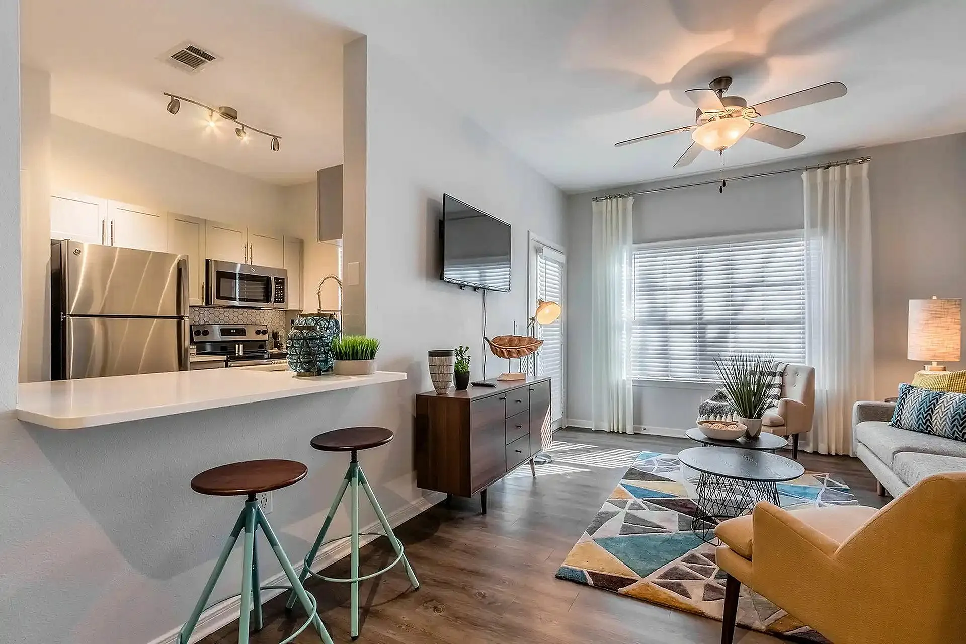 Contemporary open-concept living area with stylish kitchen, modern appliances, cozy seating and vibrant decor.