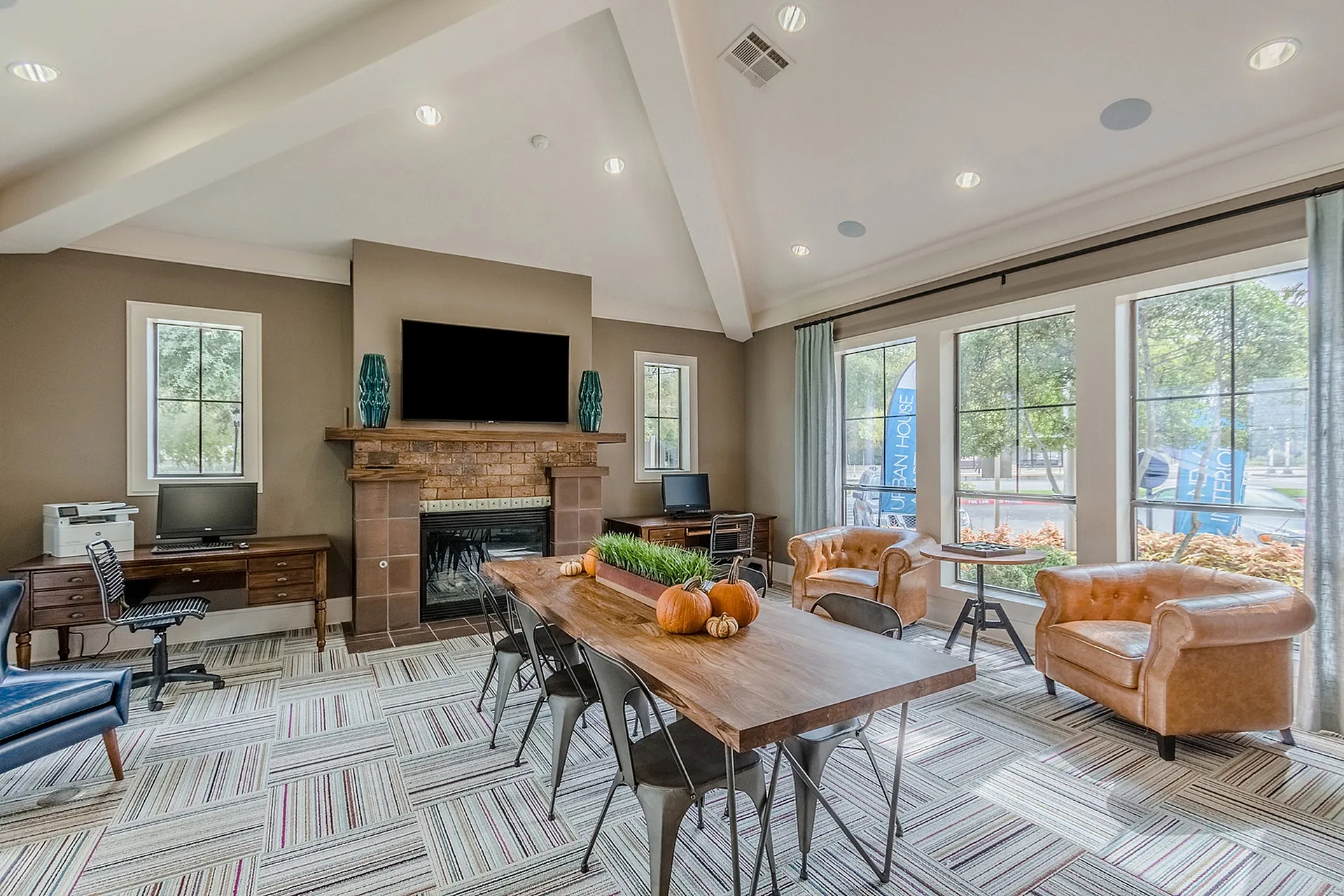 Inviting communal area with large windows, cozy armchairs, a rustic wooden table, and modern workspace, perfect for relaxation and productivity.