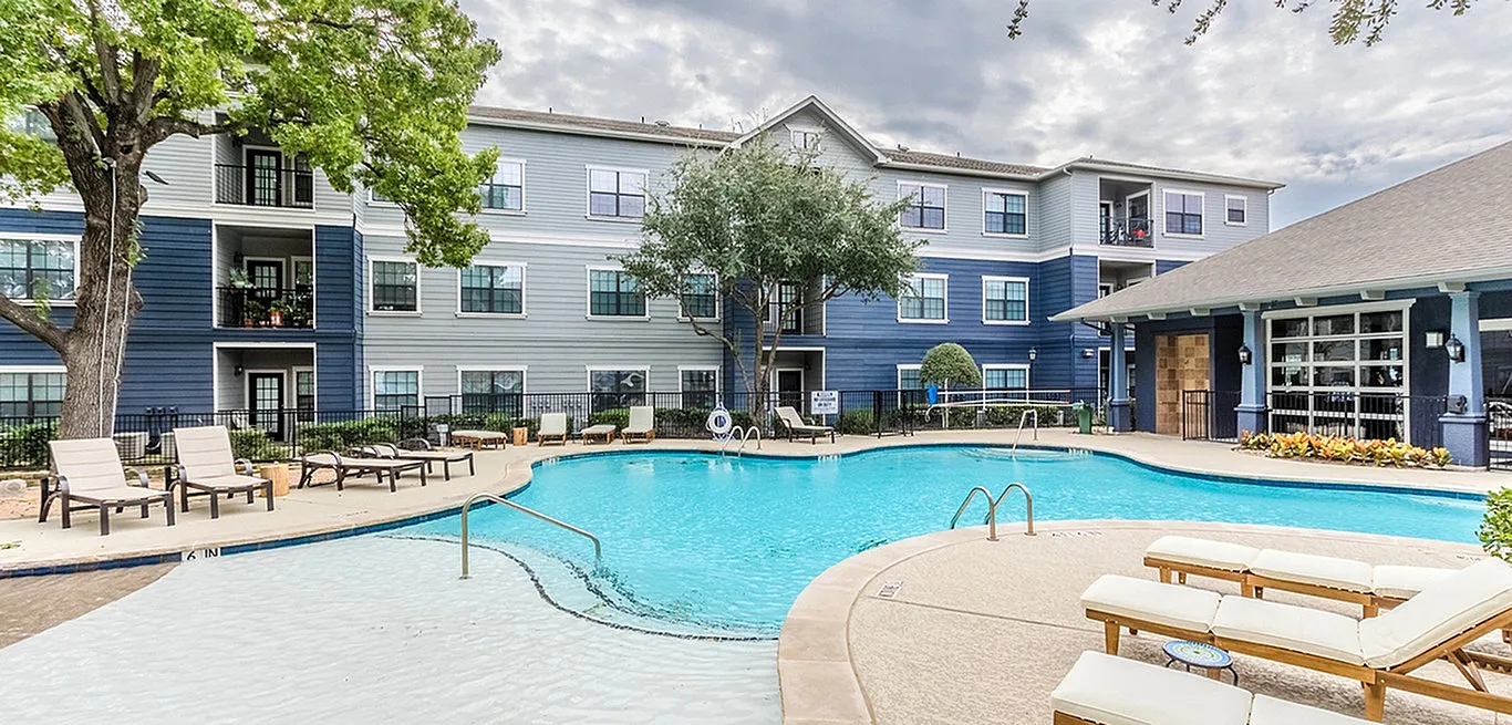Inviting apartment complex with a stunning outdoor pool area, featuring elegant loungers and lush greenery, perfect for relaxation.