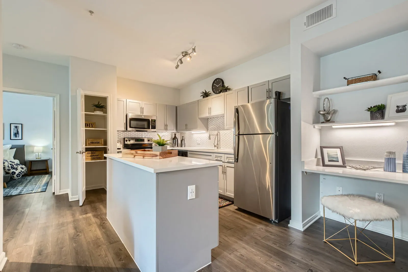 Chic modern kitchen with stainless steel appliances, elegant cabinetry, and a cozy workspace in a stylish apartment.