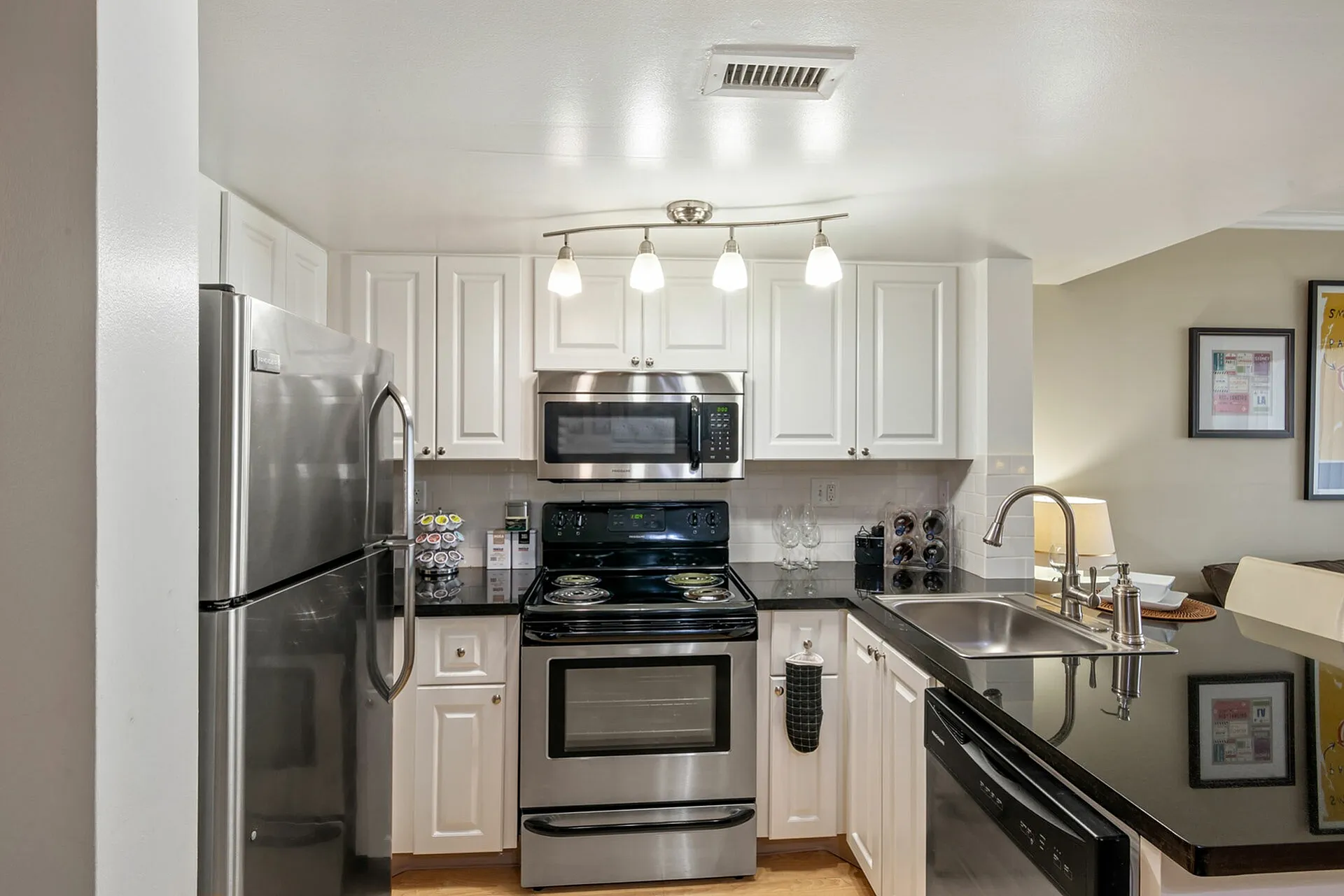 Sleek modern kitchen with stainless steel appliances, glossy black countertops, and elegant white cabinetry.