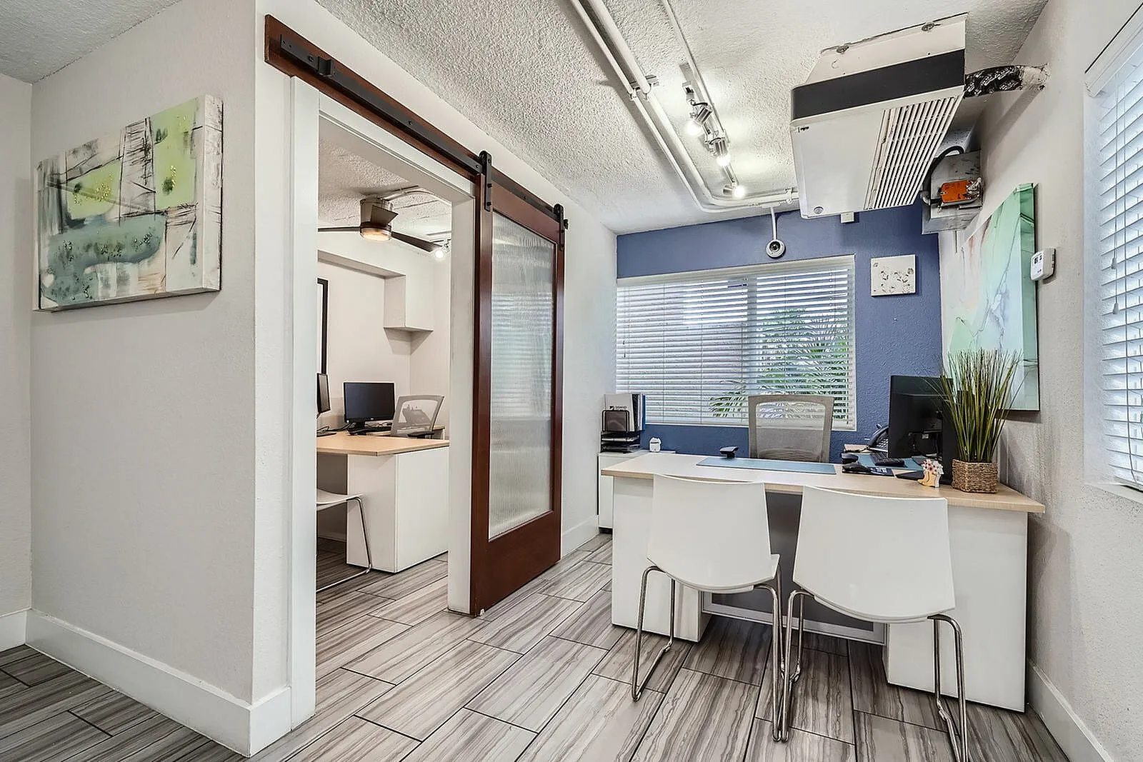 Modern office space featuring sleek furnishings, contemporary art, and a spacious desk area with natural light flooding through large windows.