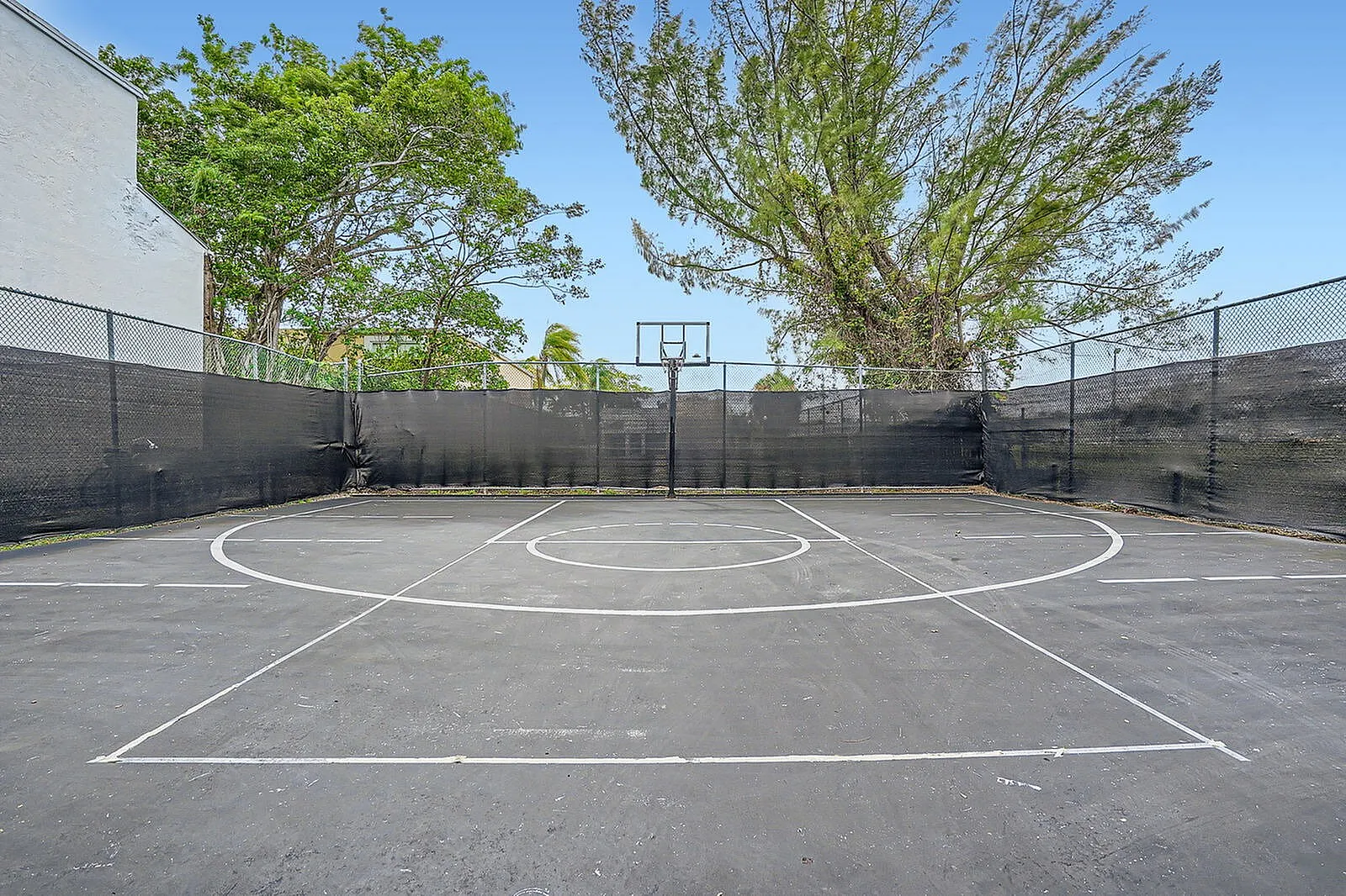 Inviting outdoor basketball court surrounded by lush greenery, perfect for recreation and leisure.