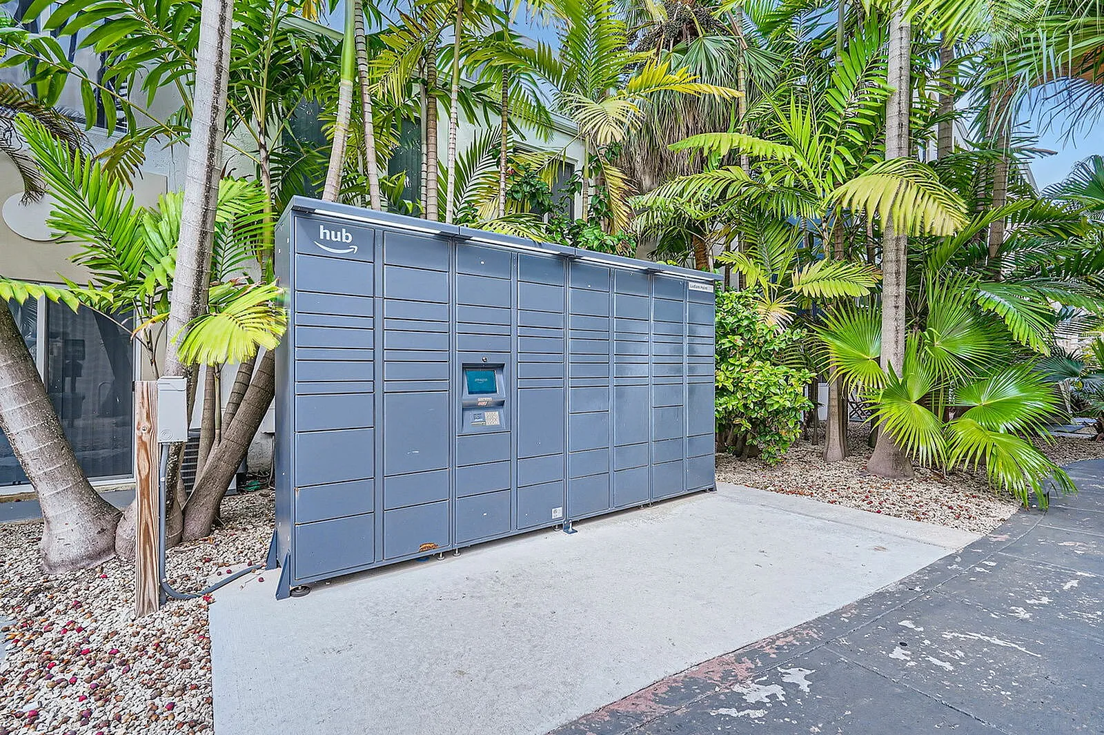 Convenient Amazon Hub locker set amid lush tropical greenery, offering easy package access for residents.