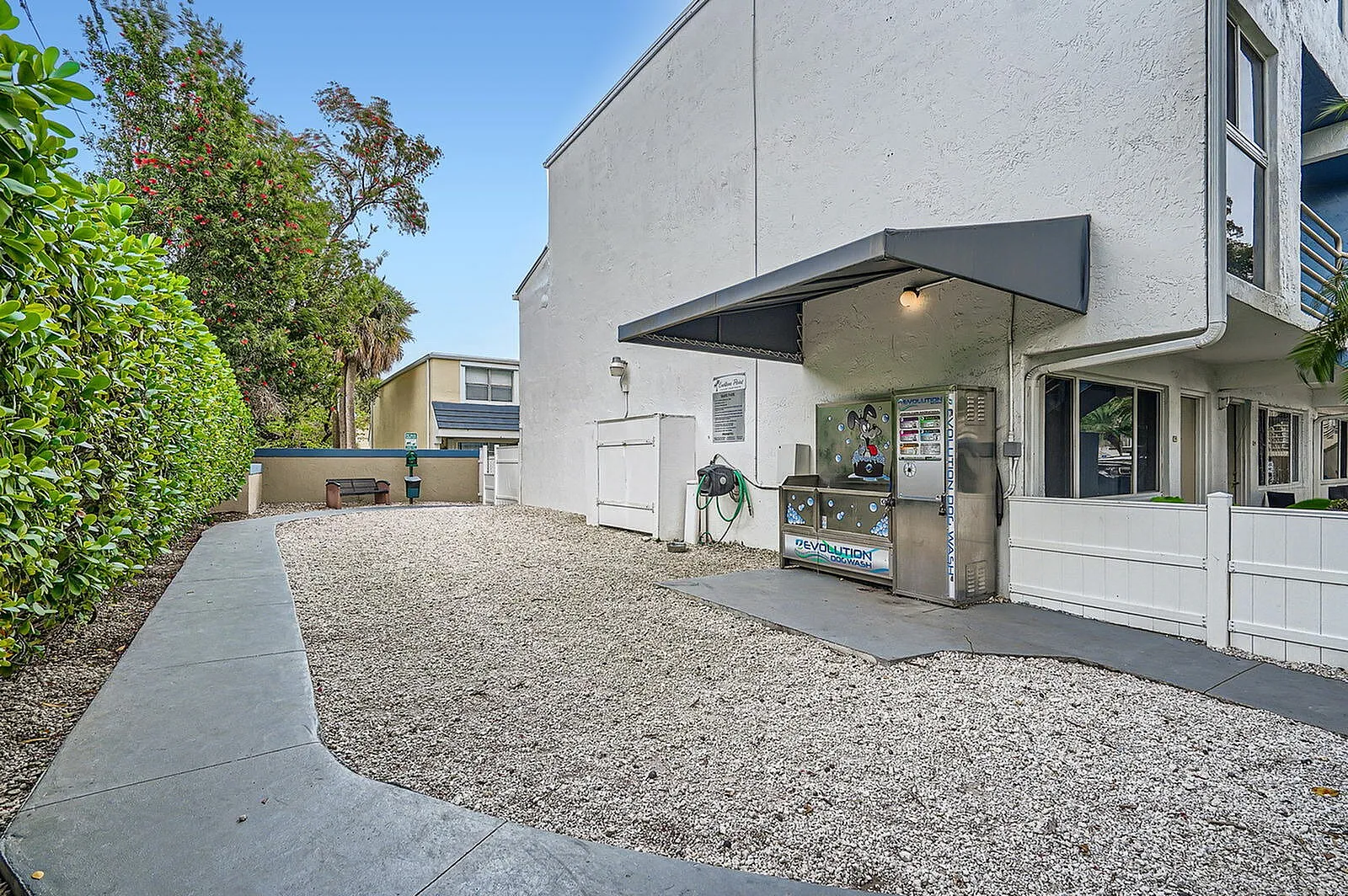 Charming outdoor area with a convenient dog wash station, framed by lush greenery and a stylish modern building.