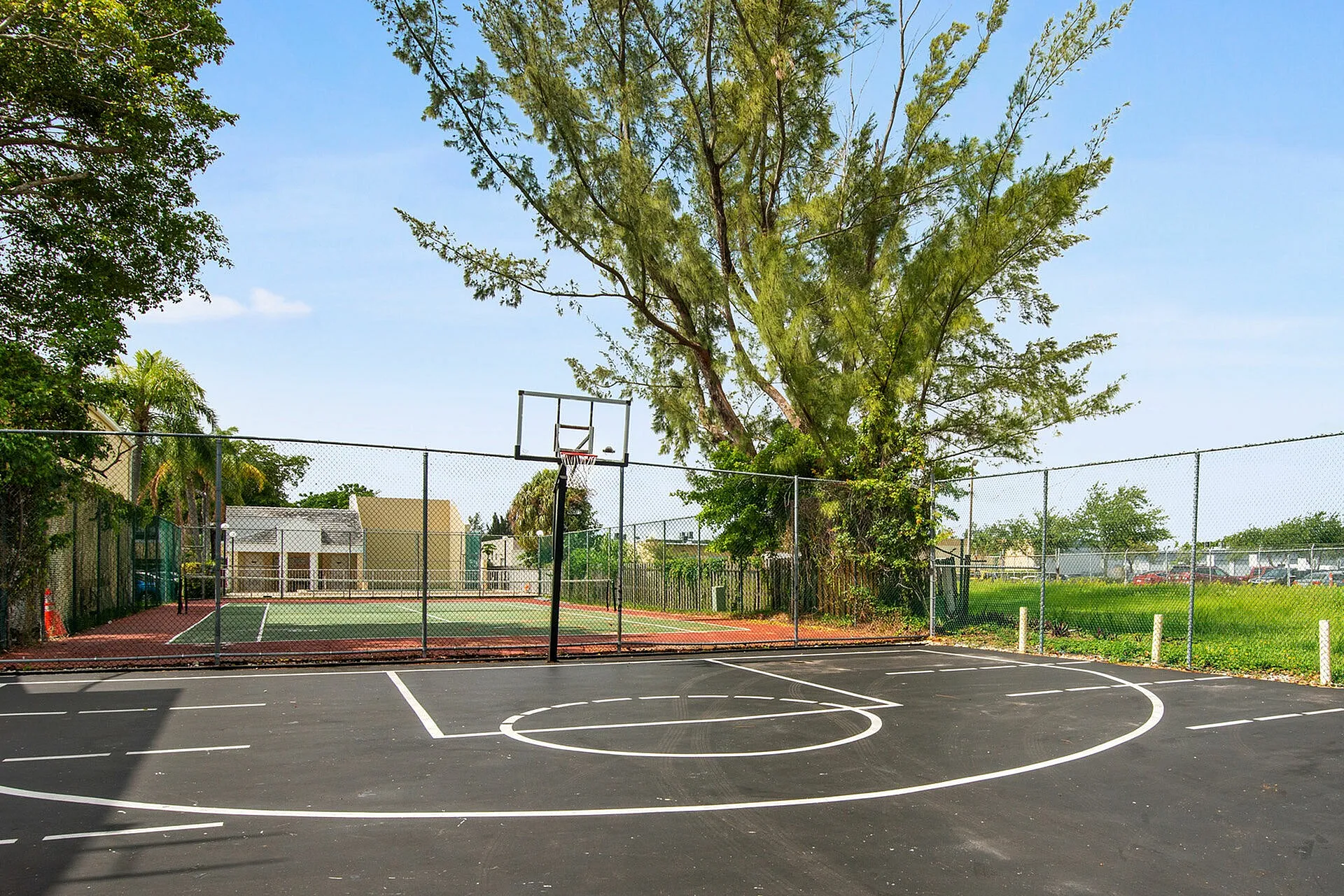 Inviting outdoor basketball court surrounded by lush greenery and clear blue skies, ideal for sports enthusiasts.