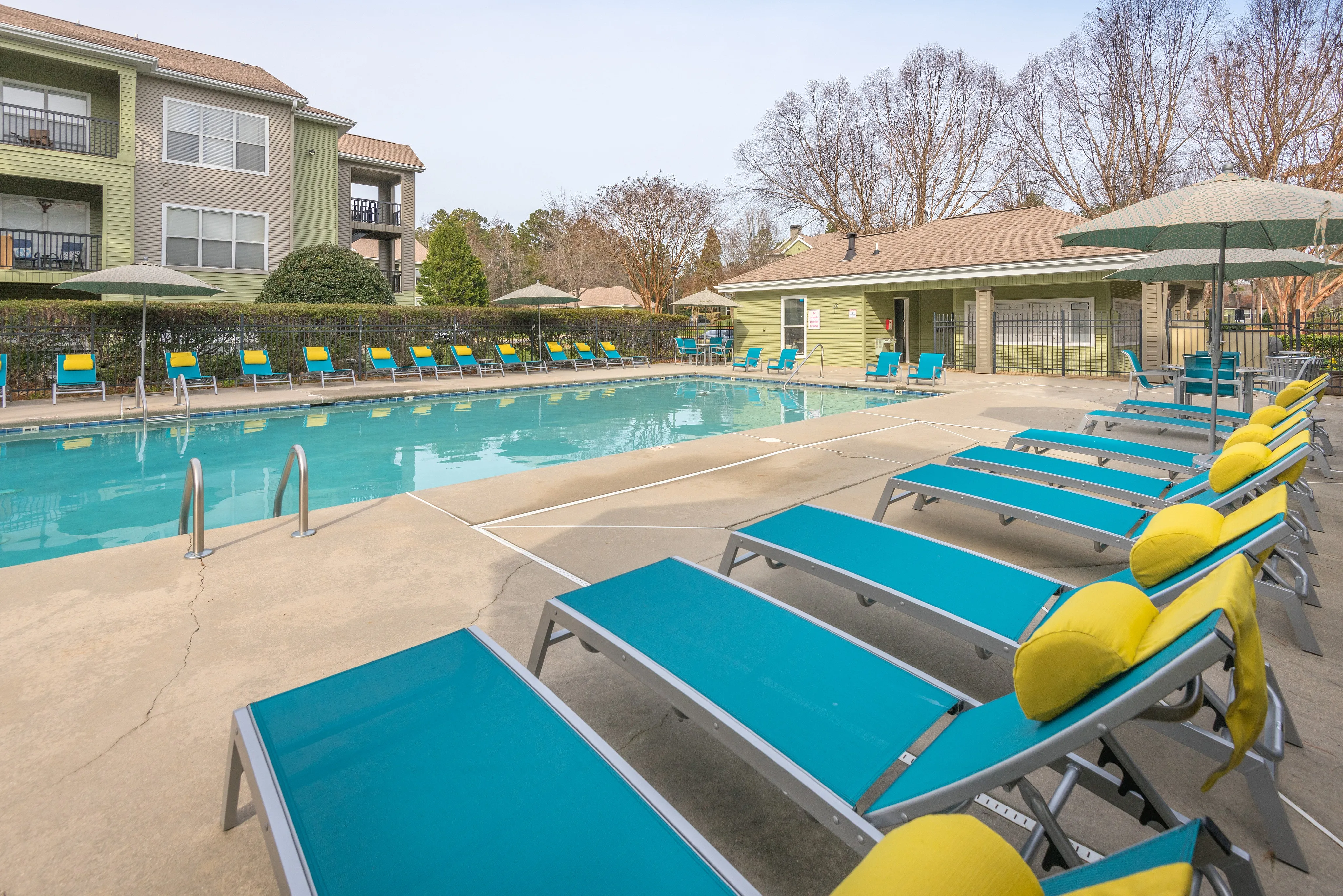 Inviting outdoor pool area with vibrant blue lounge chairs and umbrellas, perfect for relaxation and enjoying sunny days.
