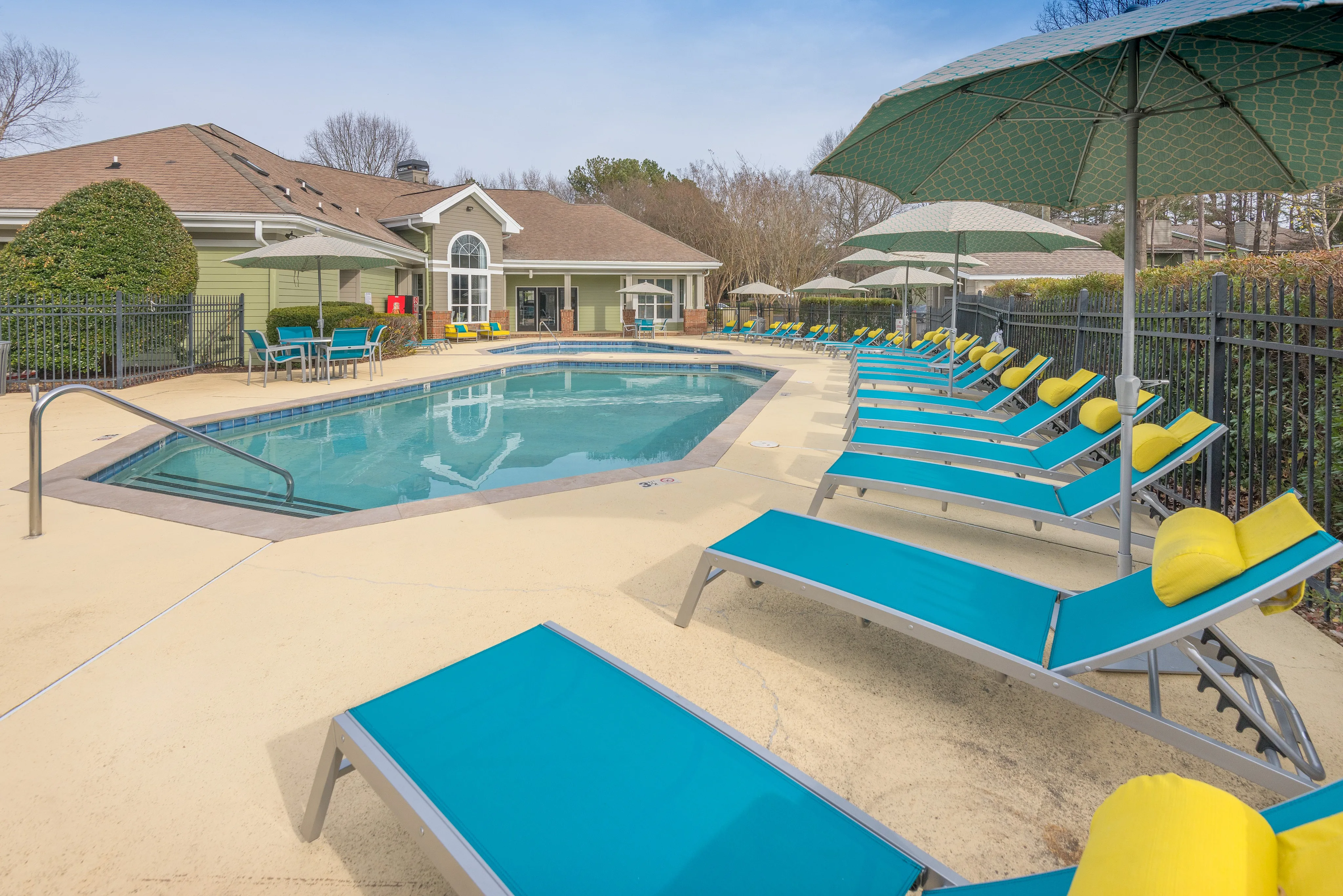 Inviting outdoor pool area with vibrant lounge chairs and umbrellas, perfect for relaxation and enjoyment.