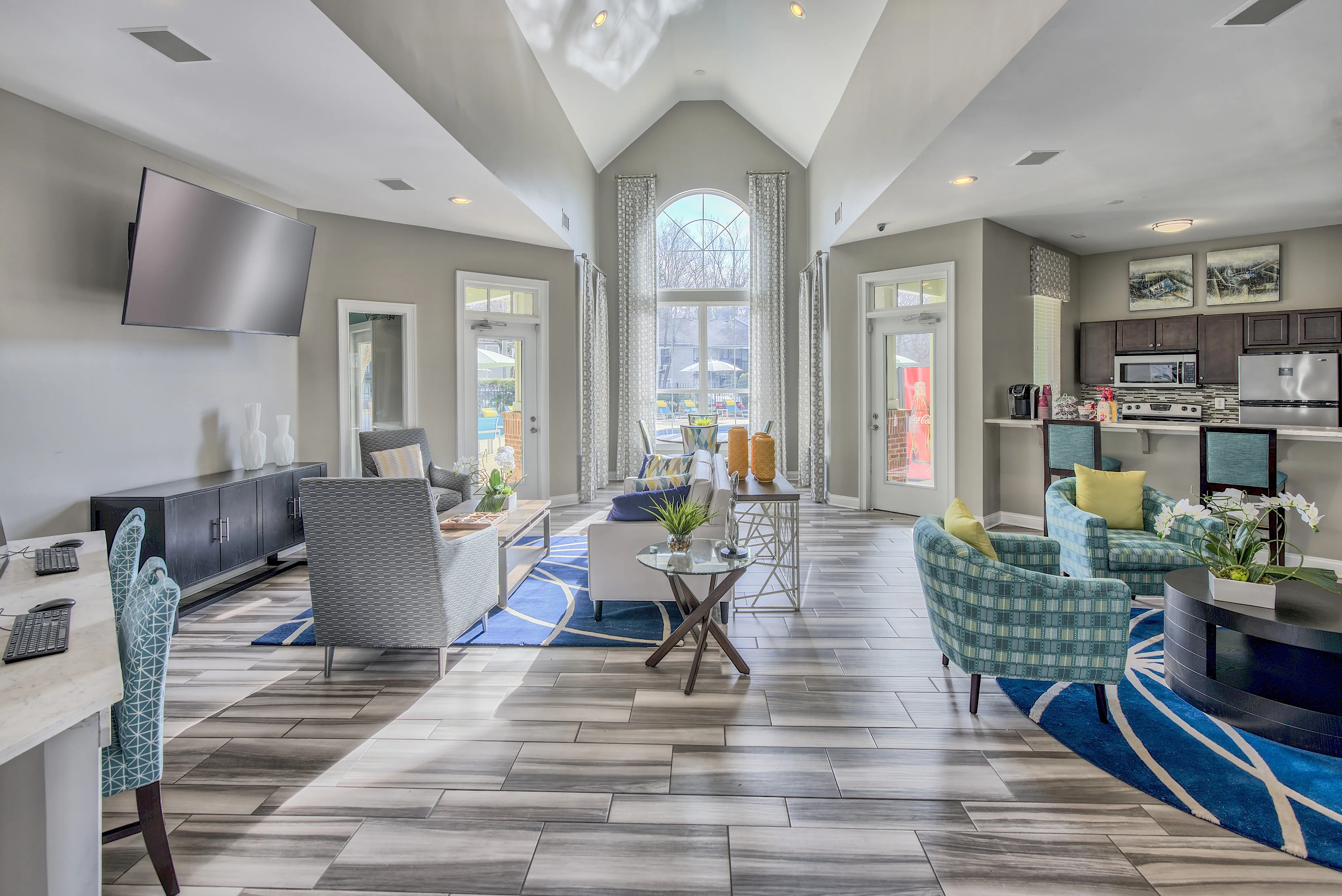 Luxurious modern living room with vaulted ceilings, elegant furnishings, and abundant natural light from large windows overlooking a vibrant outdoor space.