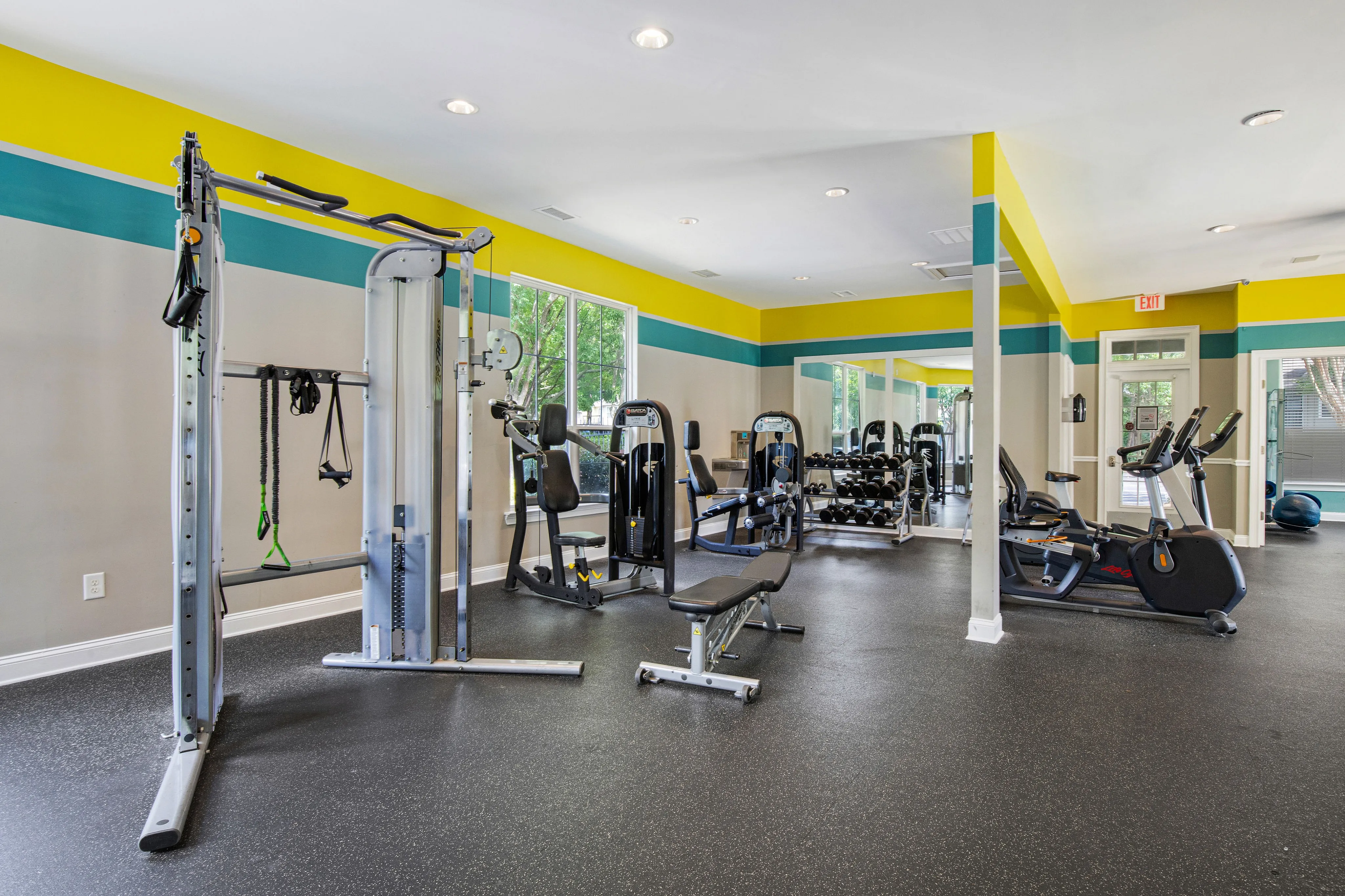 Bright, spacious gym with modern exercise equipment, vibrant decor, and ample natural light.