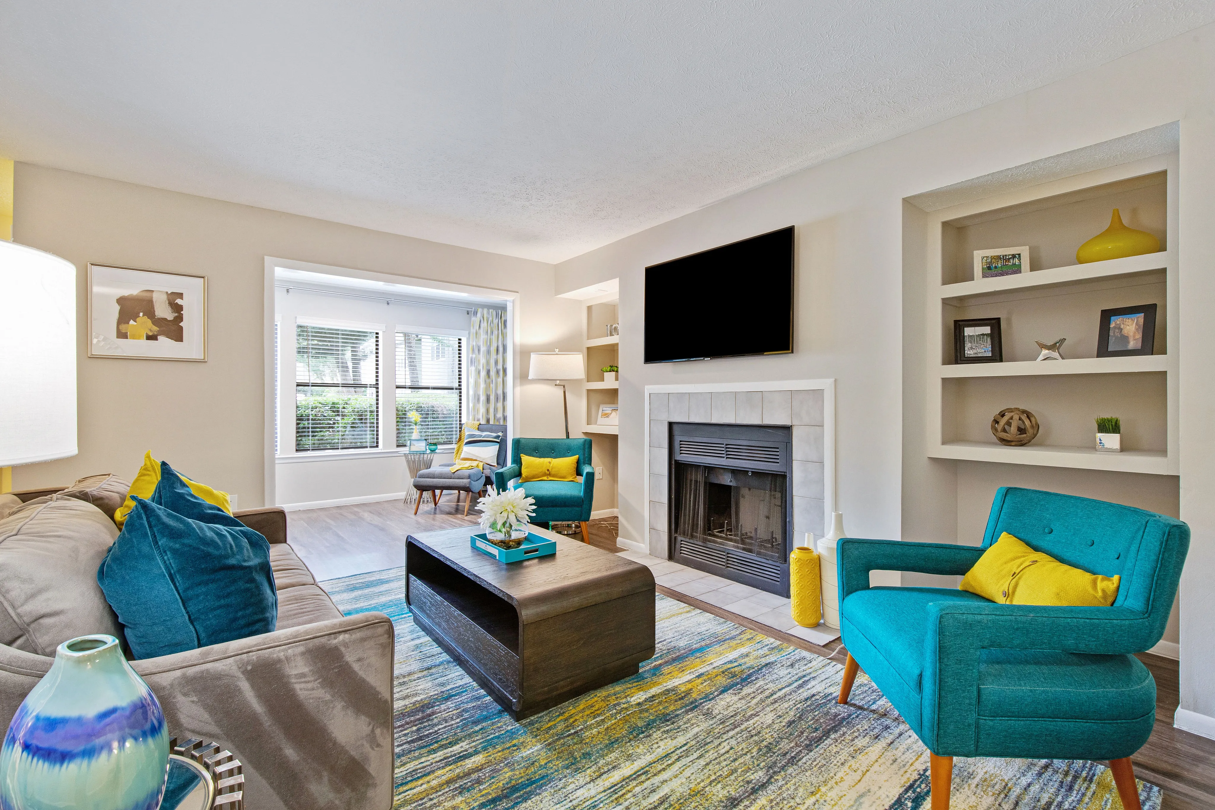 A living room with a couch, chairs, a coffee table, a flatscreen television, and large windows at The Madison apartments rentals in Charlotte, NC.