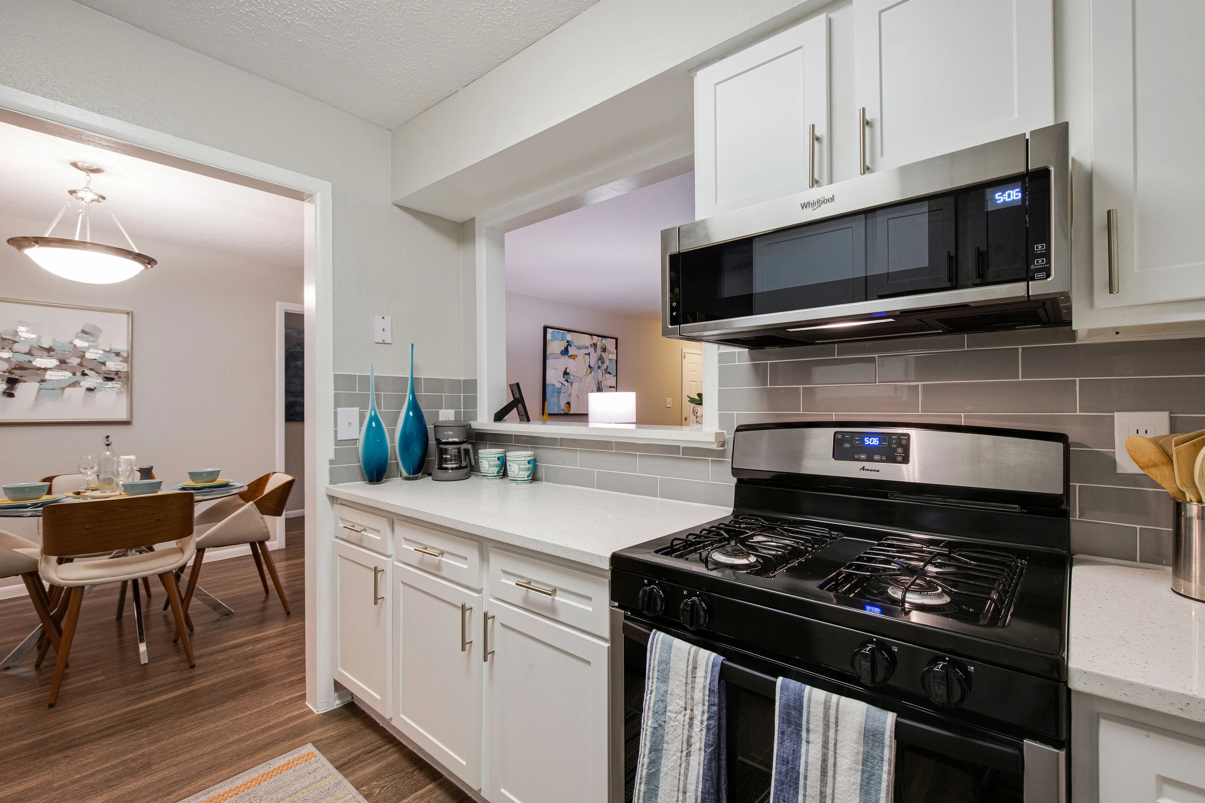 Modern kitchen with sleek white cabinets, stainless steel appliances, and a cozy dining area with elegant decor.