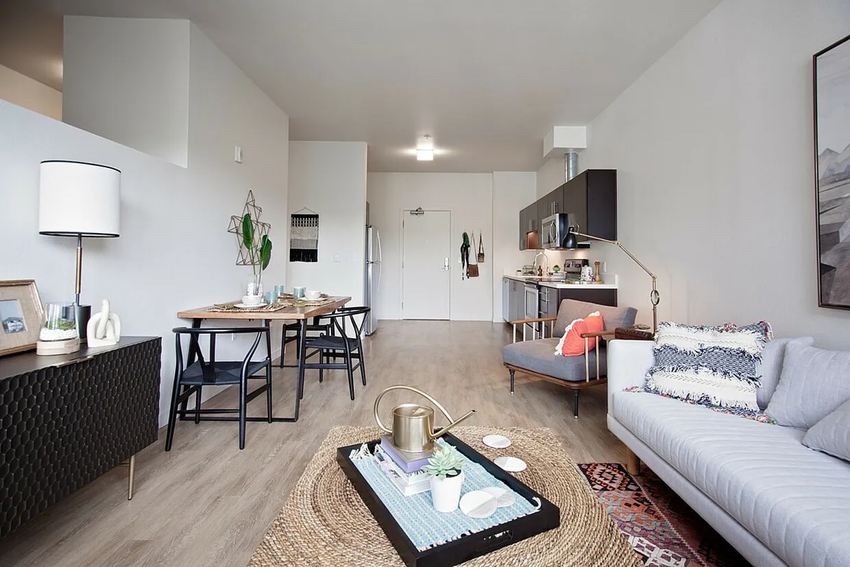 Modern open-plan living area with stylish decor, featuring a cozy sofa, elegant dining setup, and contemporary kitchen in a bright, airy space.