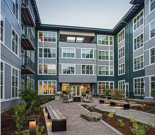 Modern apartment complex with a beautifully landscaped courtyard featuring cozy seating areas and lush greenery.