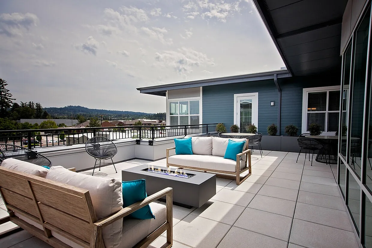 Elegant rooftop terrace with modern outdoor sofas, vibrant blue cushions, and a sleek fire pit, offering stunning panoramic views.