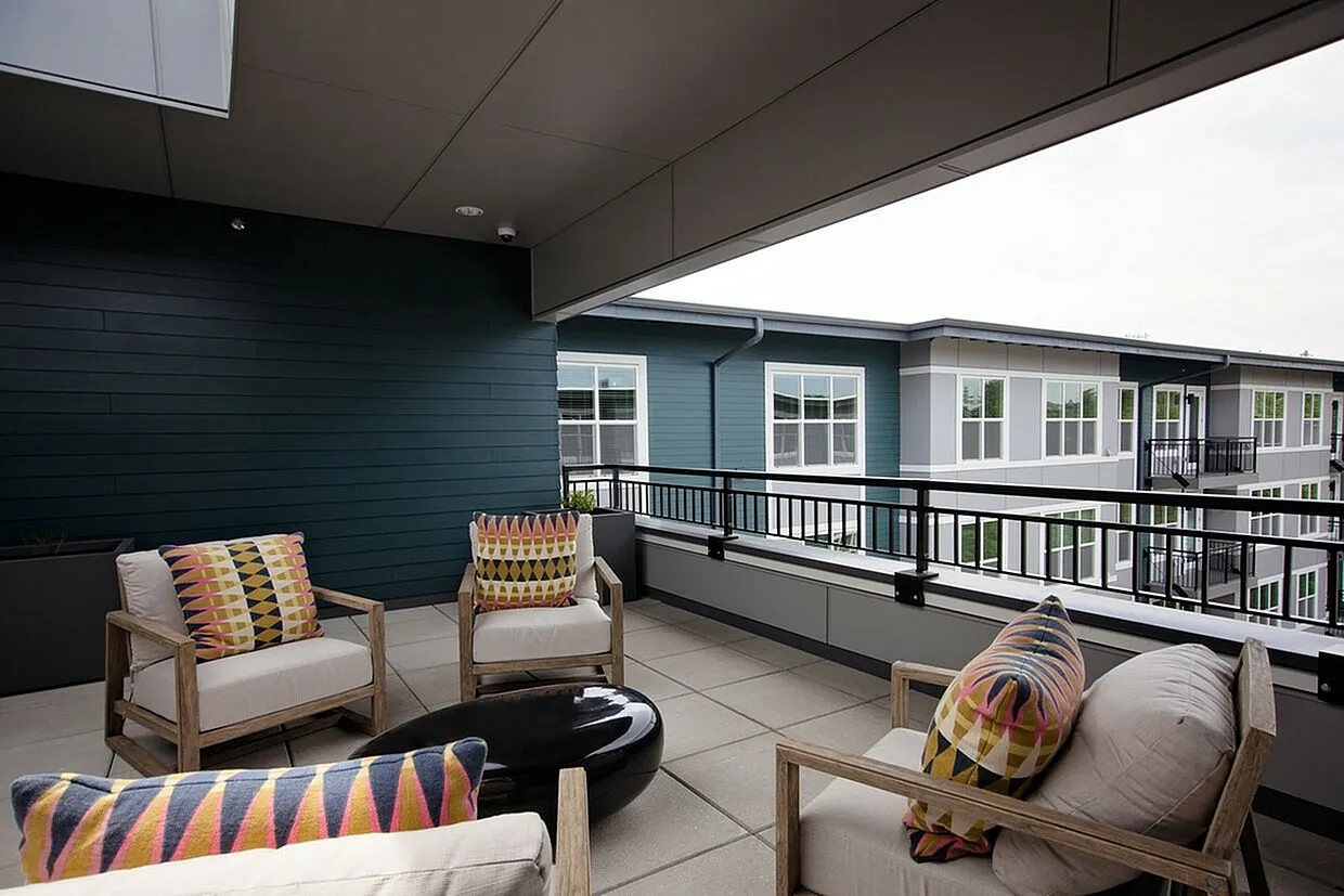 Chic and modern apartment balcony with cozy outdoor seating and vibrant cushions, offering a relaxing space with scenic views.