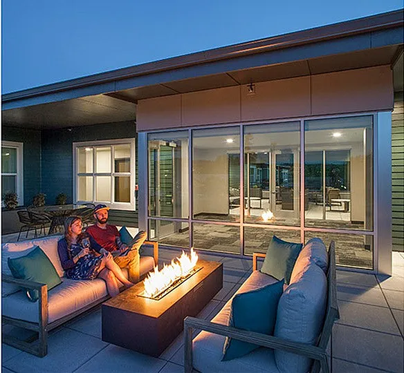 Chic rooftop patio with cozy fire pit, elegant seating arrangements, and modern architecture under a serene evening sky.