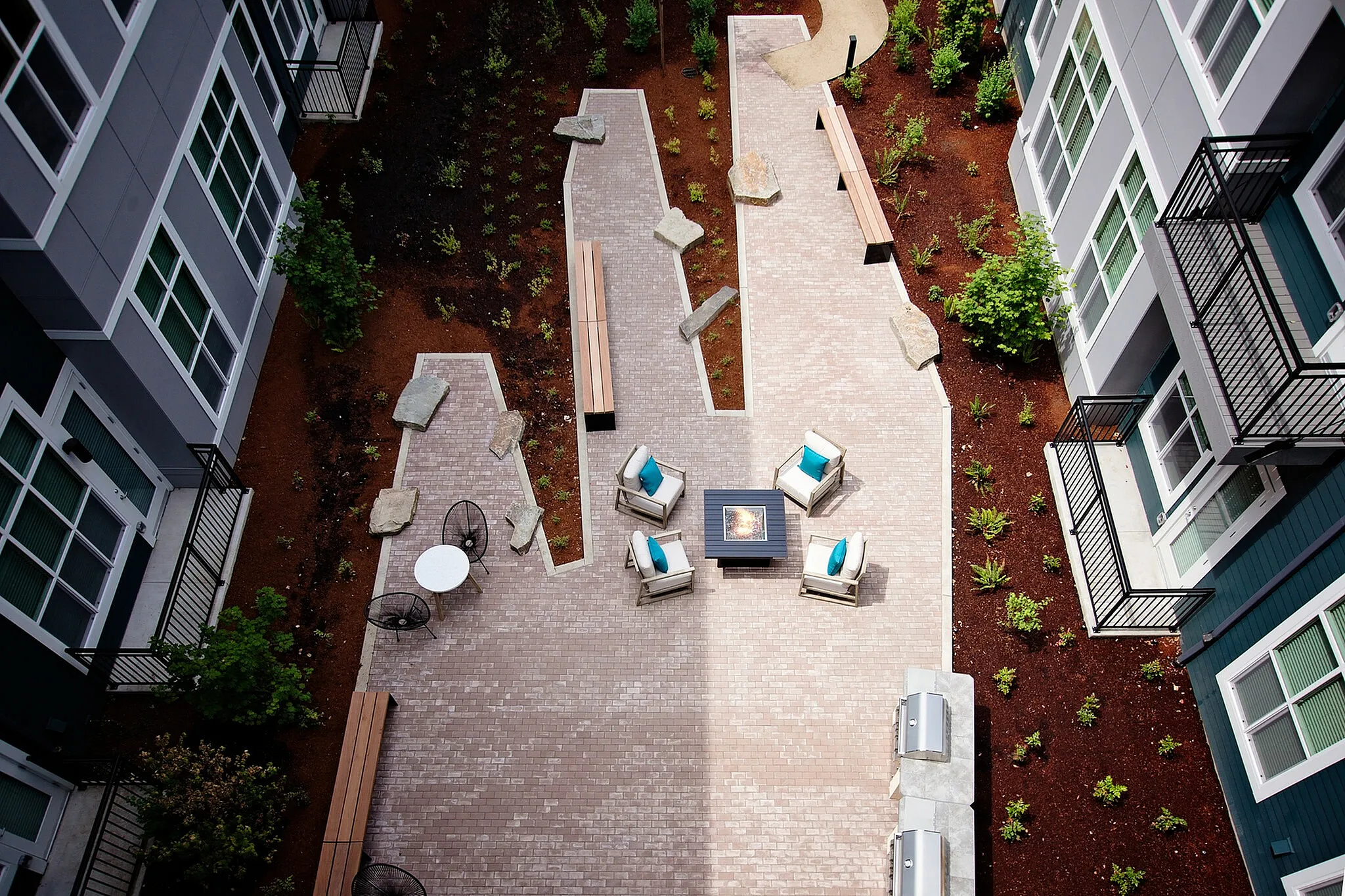 Chic and inviting courtyard featuring cozy seating around a modern fire pit, complemented by lush landscaping and stylish outdoor furniture.