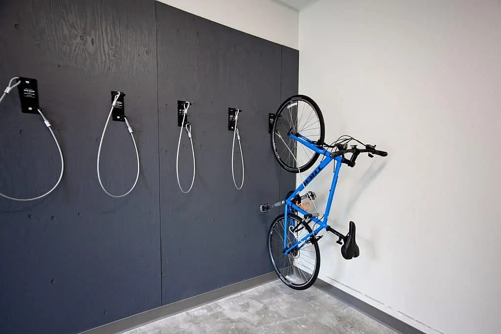 Modern bike storage wall in apartment complex with mounted blue bicycle for convenience and space-saving.