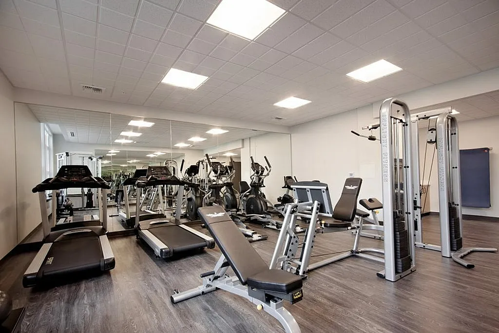 Modern fitness center with sleek treadmills, exercise bikes, and versatile strength training machines in a bright, spacious room with mirrored walls.