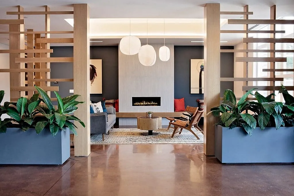 Contemporary living room with elegant lighting, lush greenery, and a modern fireplace, creating a cozy and inviting atmosphere.