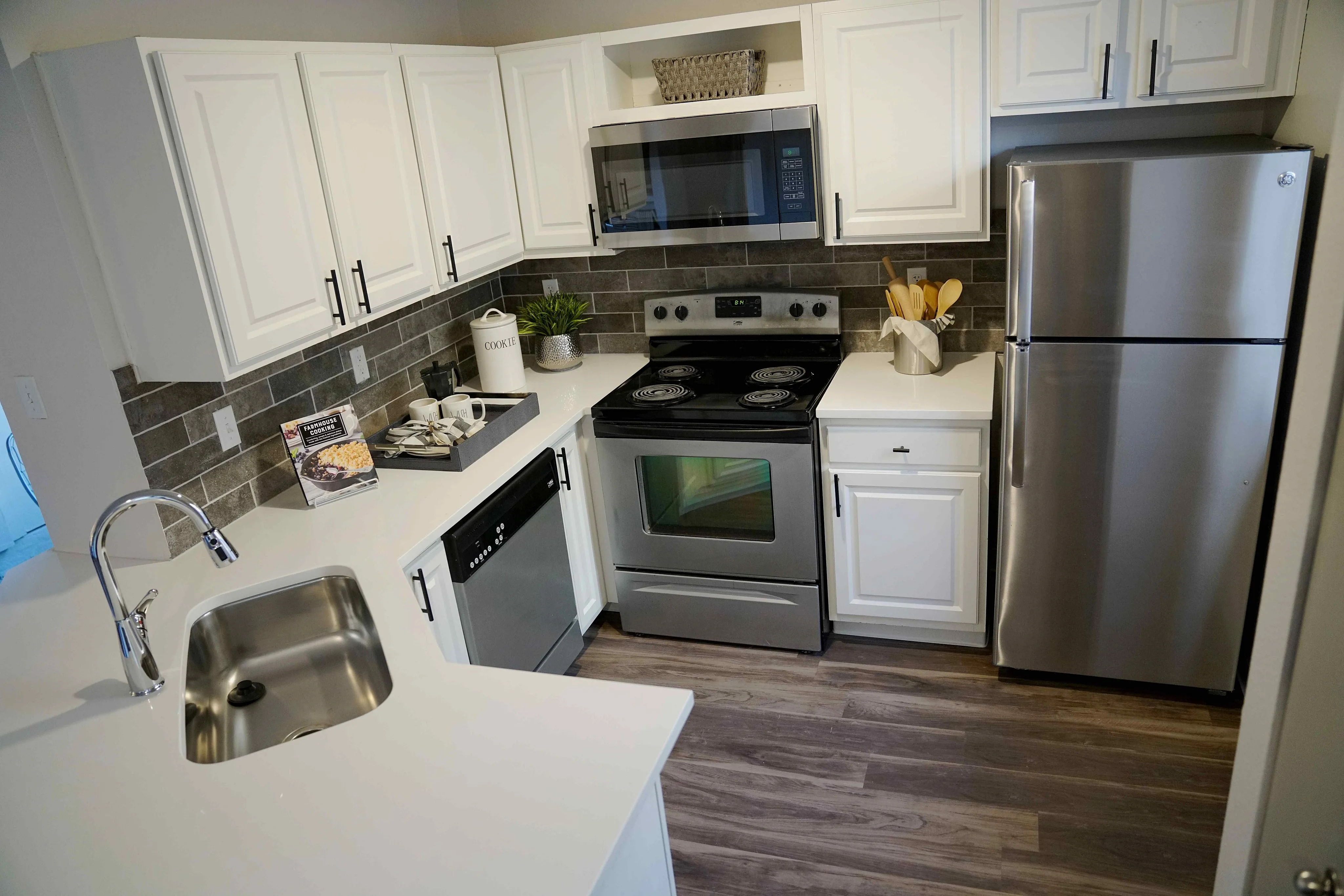 Modern kitchen with sleek stainless steel appliances, elegant white cabinetry, and stylish dark tile backsplash.
