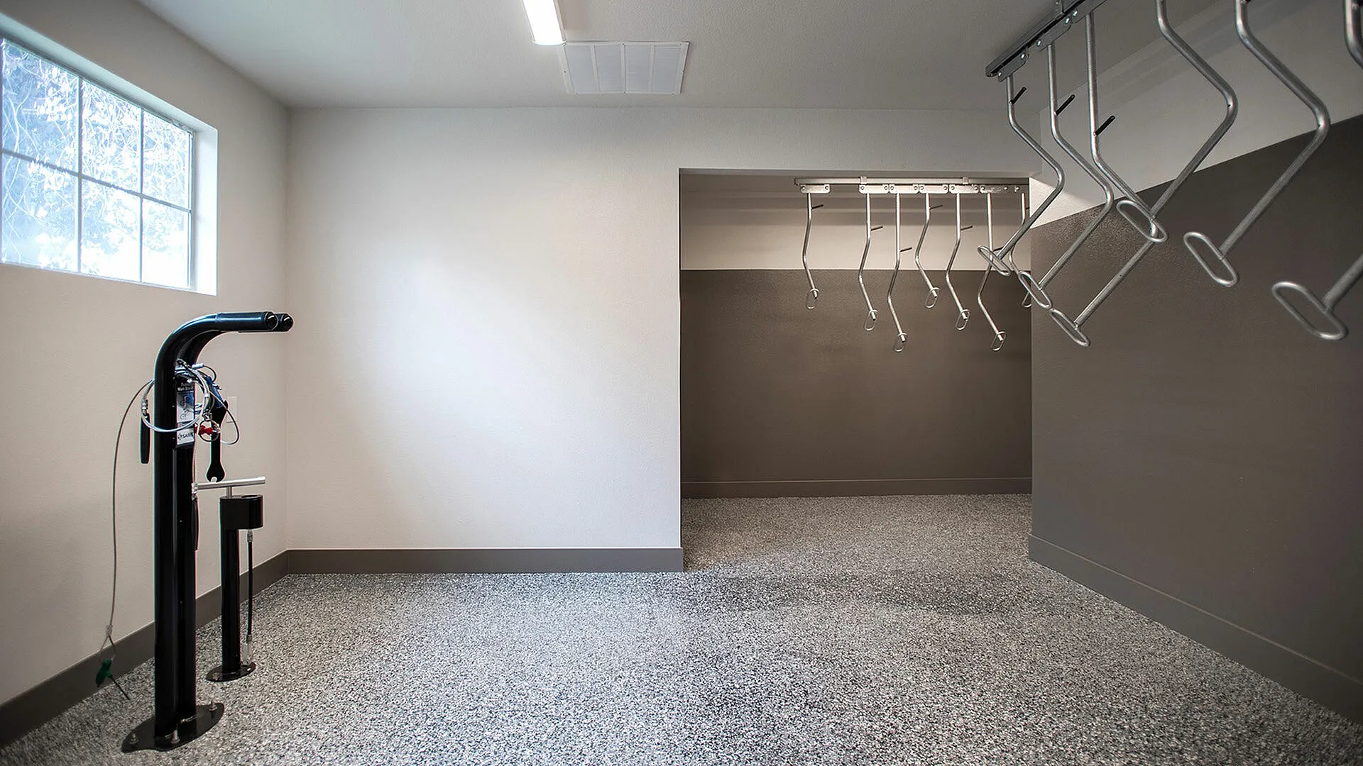 Modern and spacious bike storage room with gleaming speckled flooring, ample hanging racks, and natural light.