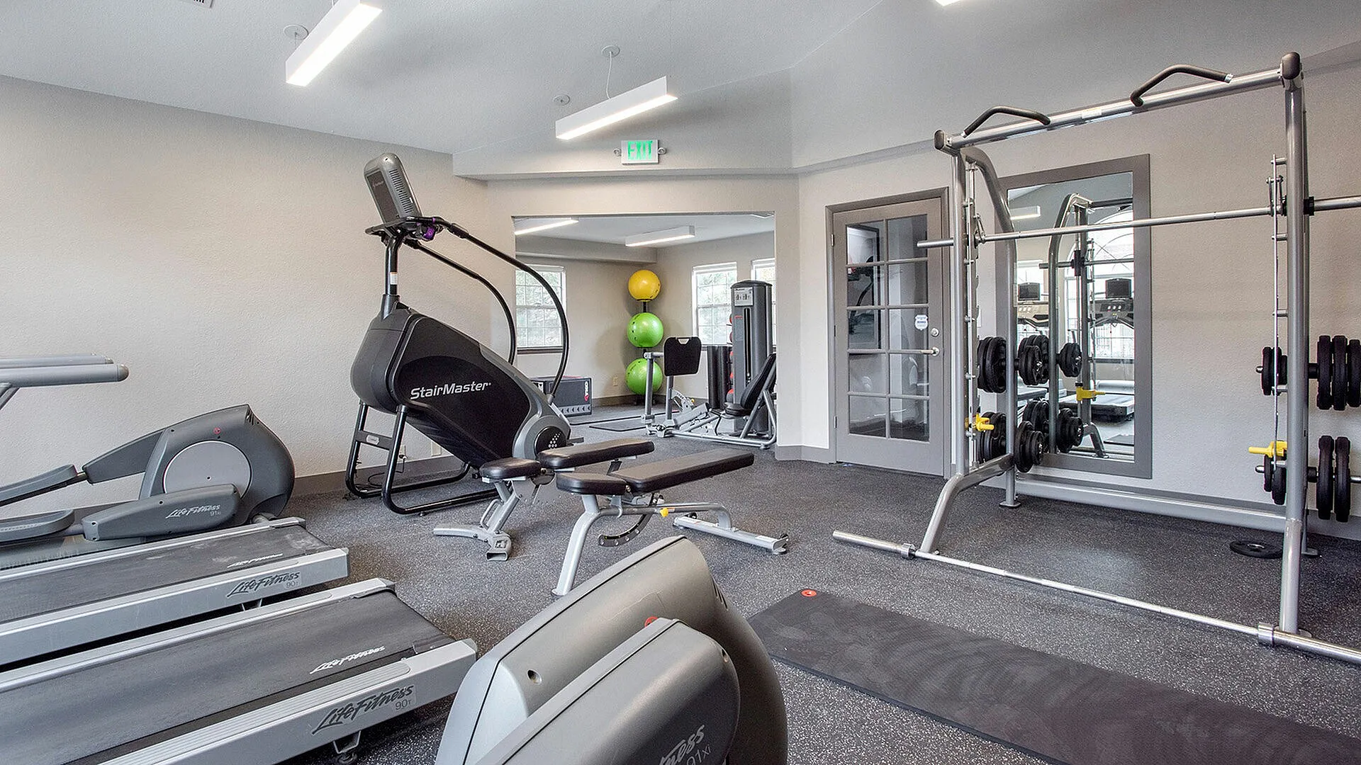 Modern fitness center with state-of-the-art equipment including treadmills, StairMaster, and weightlifting area, perfect for an active lifestyle.