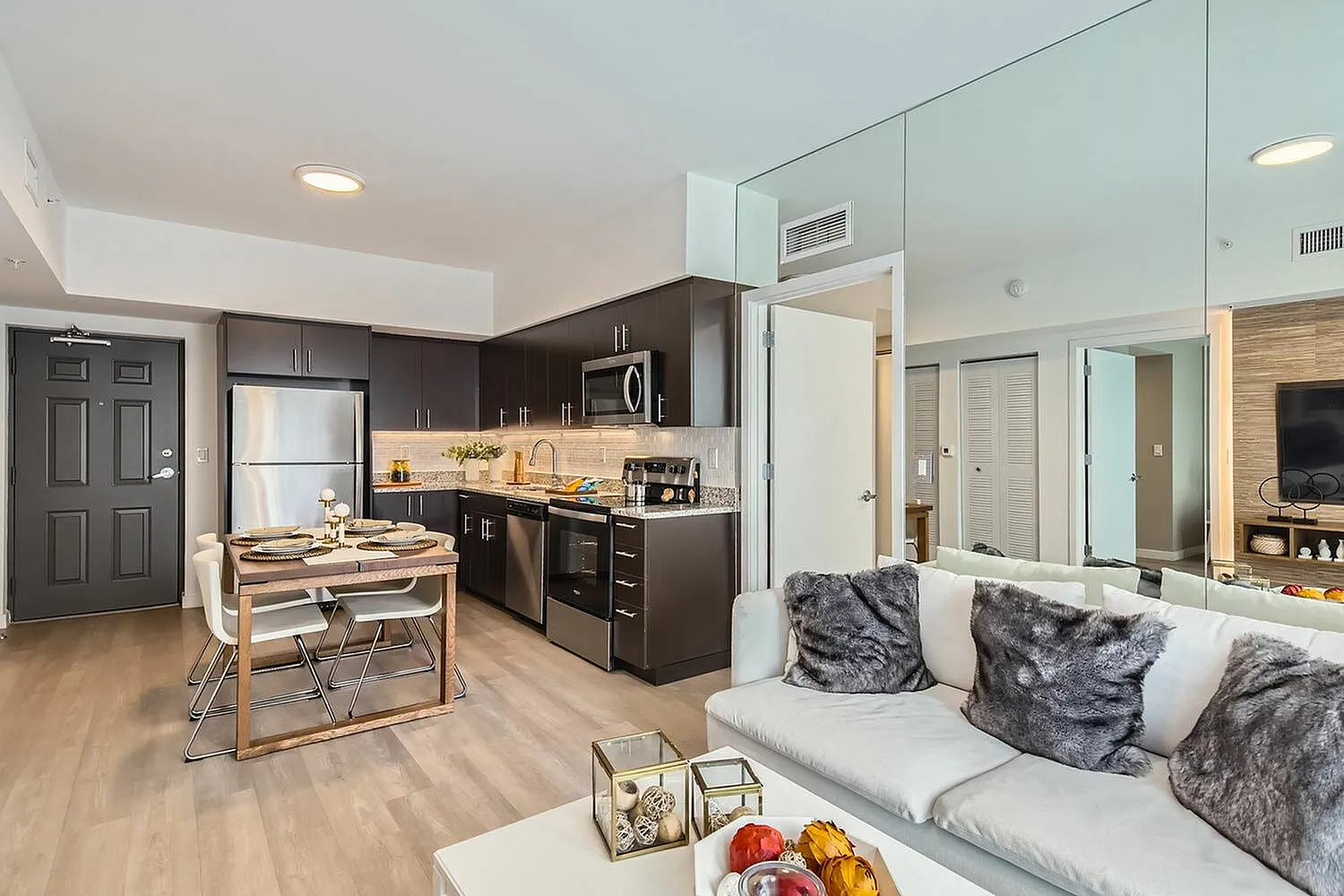 Sleek and modern open-concept kitchen and living area featuring dark cabinetry, stainless steel appliances, and elegant decor.