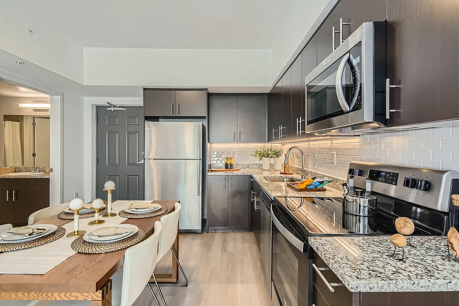 Modern kitchen with sleek dark cabinets, stainless steel appliances, and a stylish dining area set with elegant tableware.