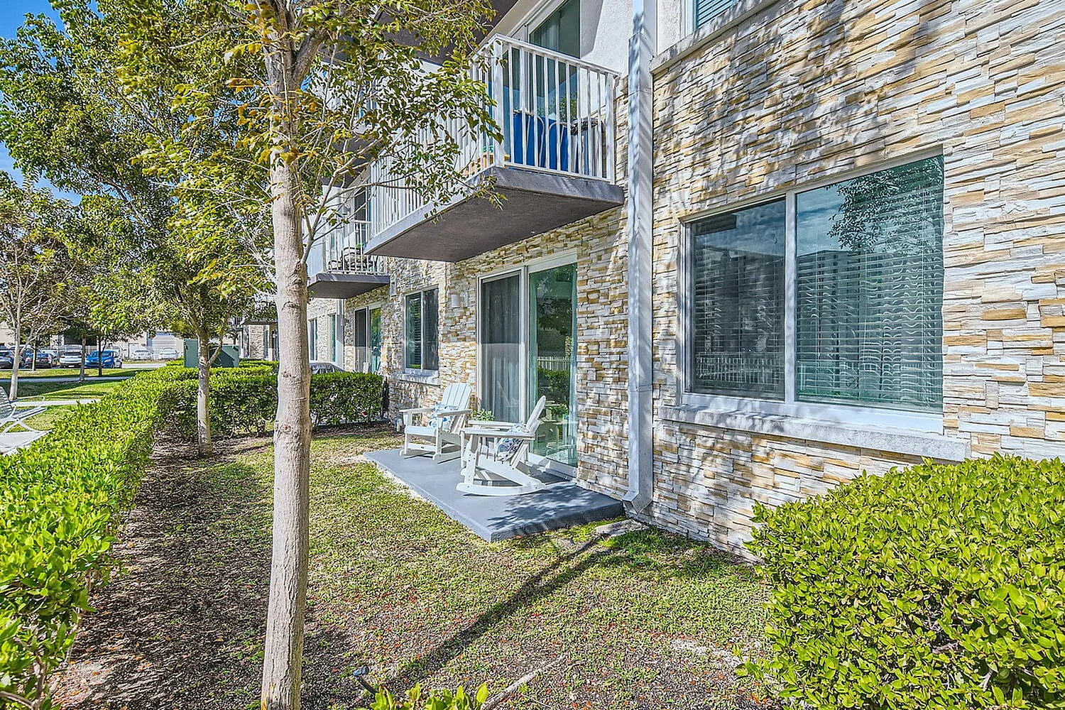 Charming apartment balcony with stylish stonework, overlooking lush greenery and well-maintained landscaping.