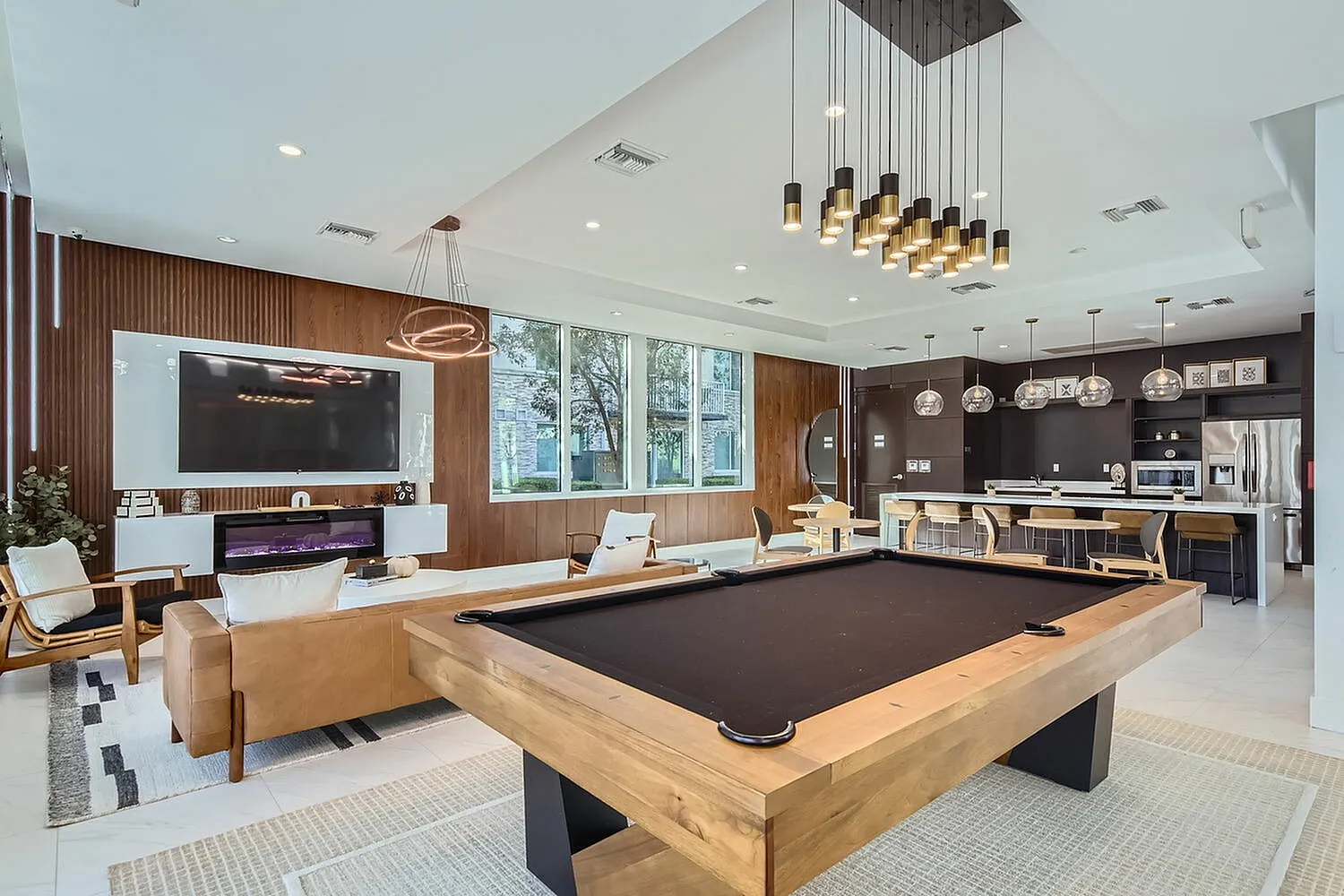 Luxurious open-concept living area with modern decor, featuring a pool table, stylish lounge, and sleek kitchen with state-of-the-art appliances.