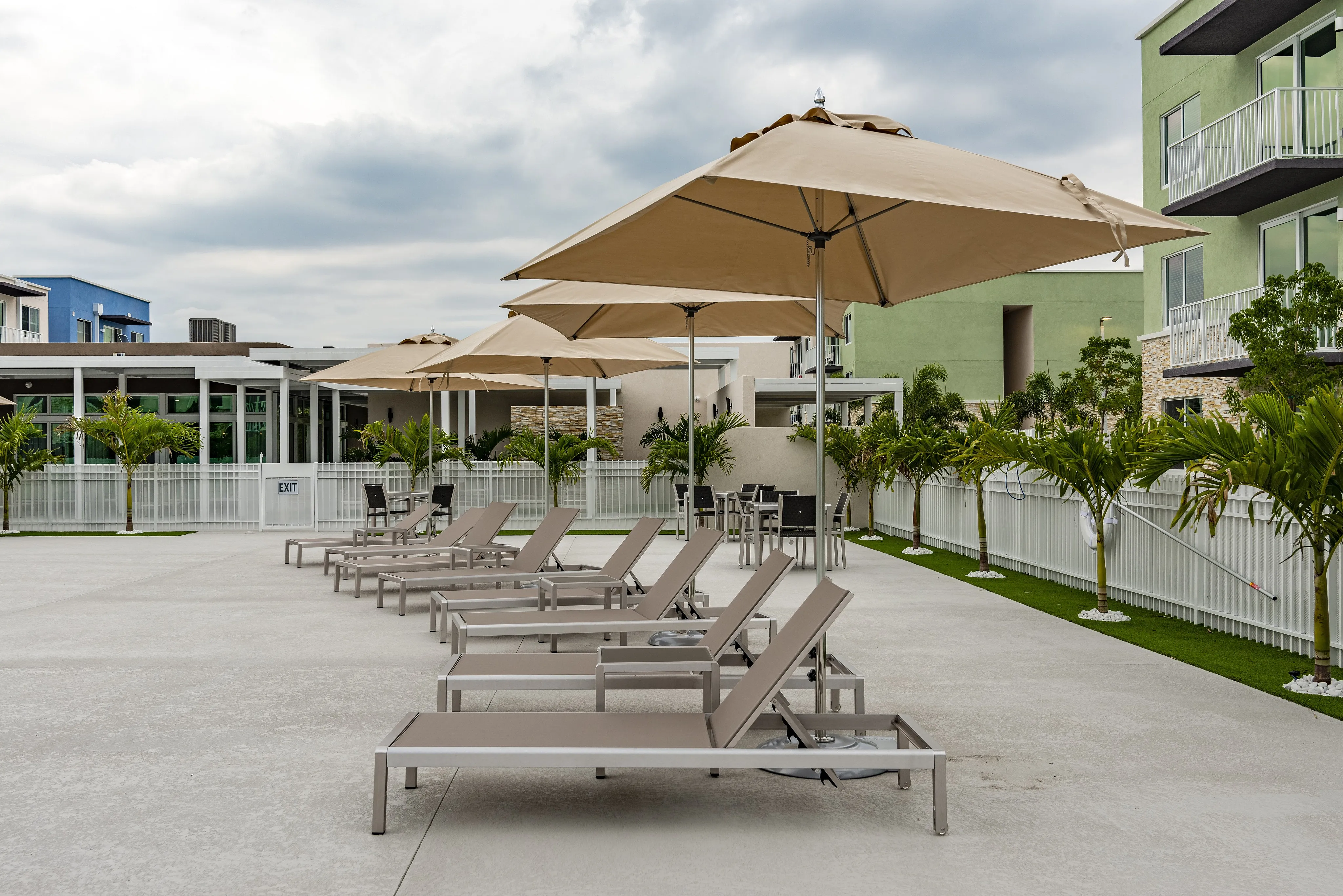 Luxurious outdoor lounge area with stylish sun loungers and large umbrellas, perfect for relaxation amidst lush palm greenery.