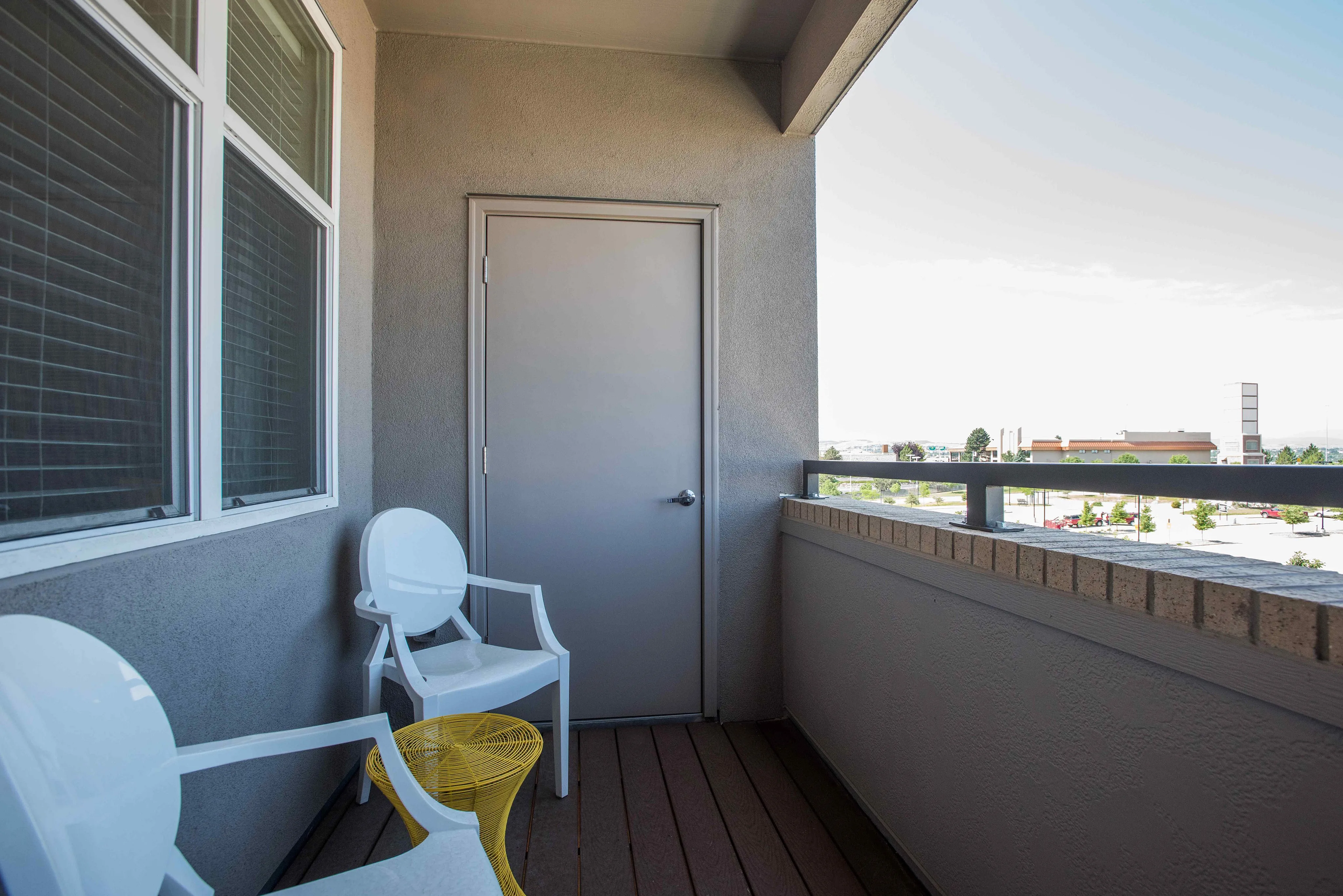 Charming balcony with two elegant white chairs and a vibrant yellow side table, perfect for relaxing and enjoying the serene view.