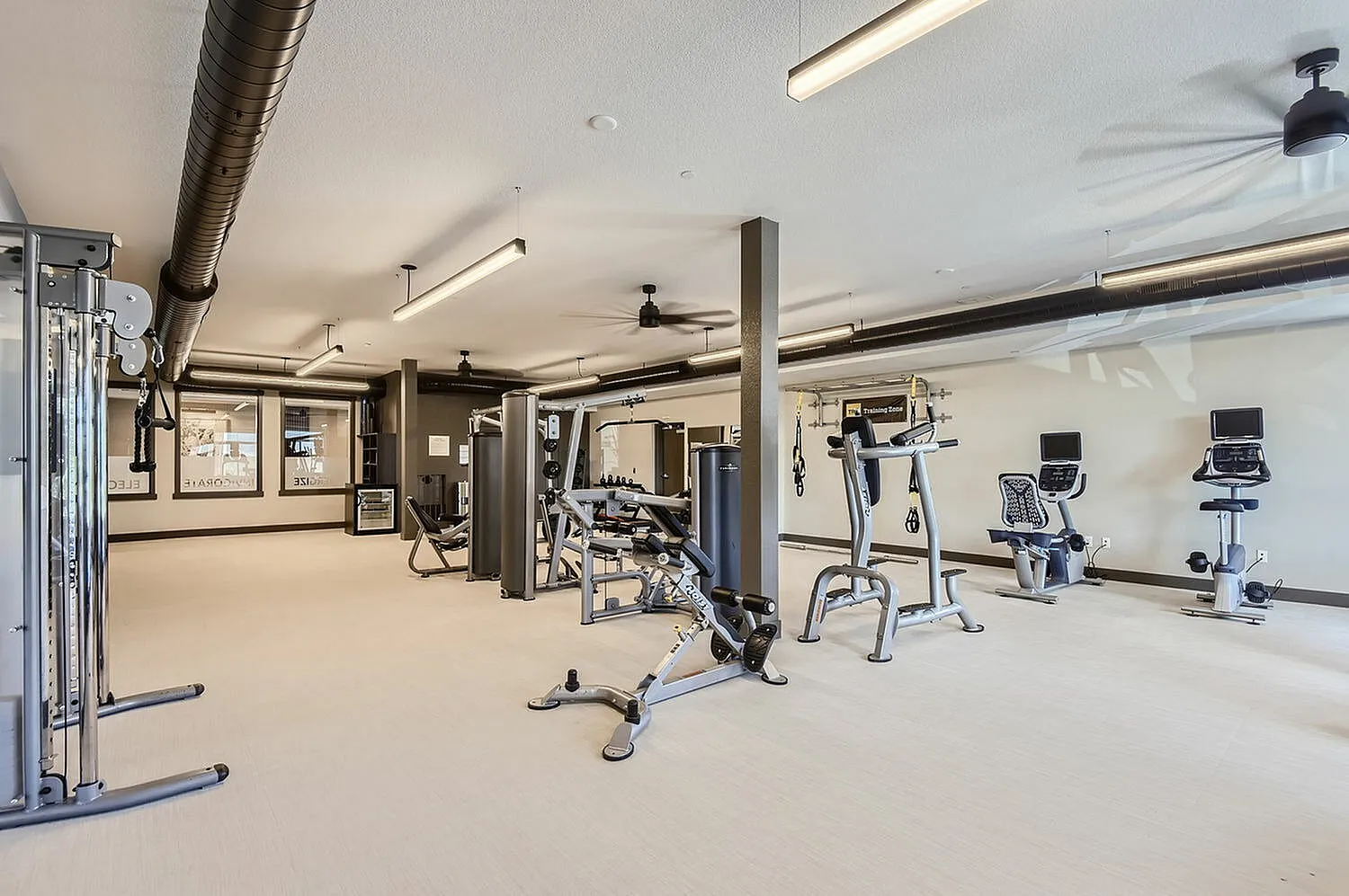 Spacious modern gym with state-of-the-art fitness equipment, sleek design, and ample workout space.