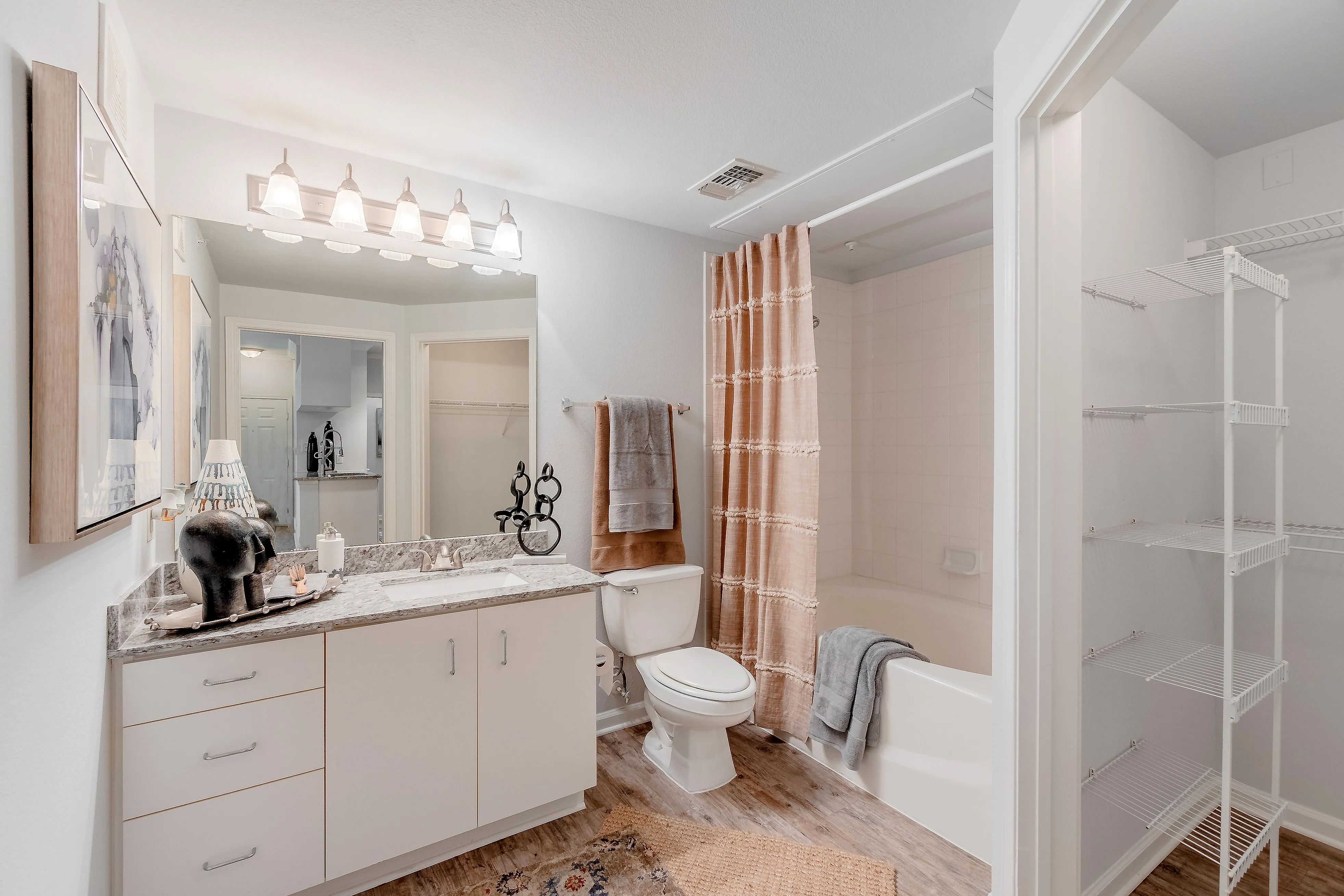 Elegant bathroom with granite countertop, stylish lighting, and a cozy bathtub behind a decorative shower curtain.