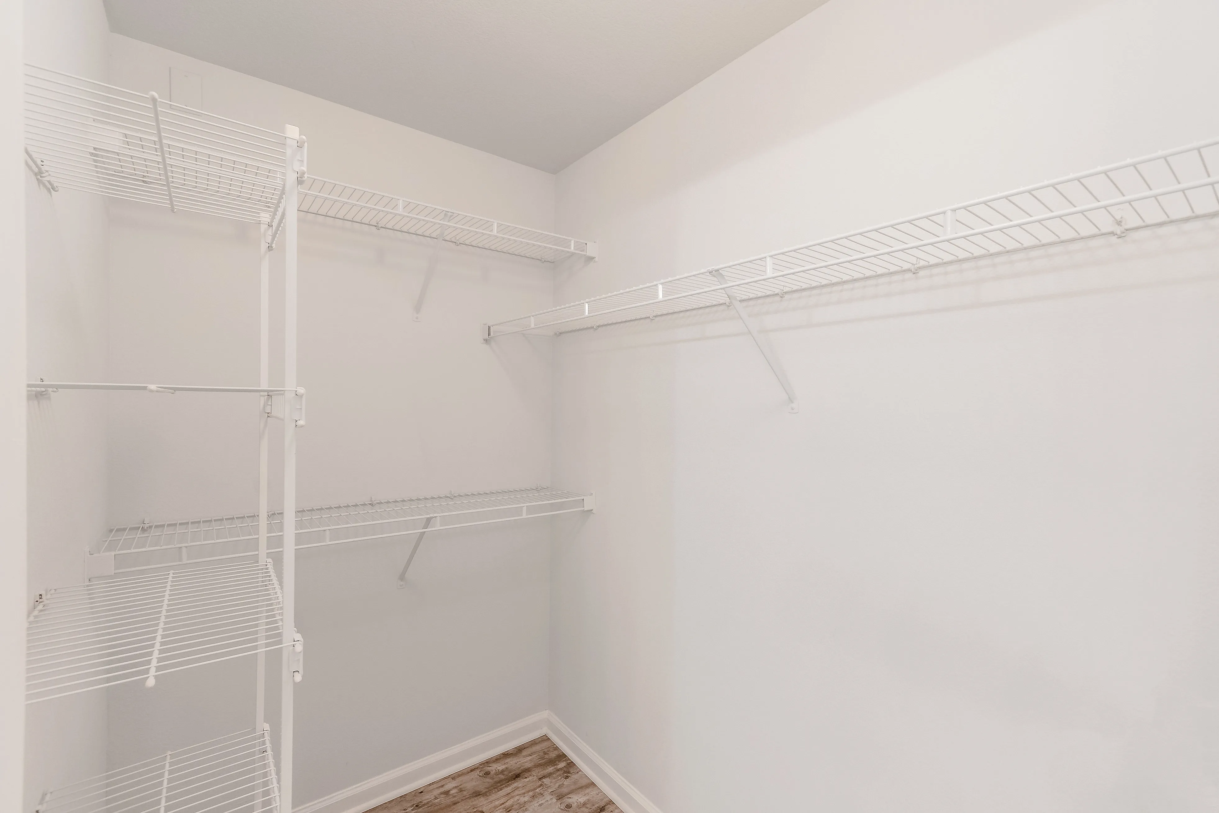 Spacious walk-in closet featuring sleek white wire shelving for ample storage.