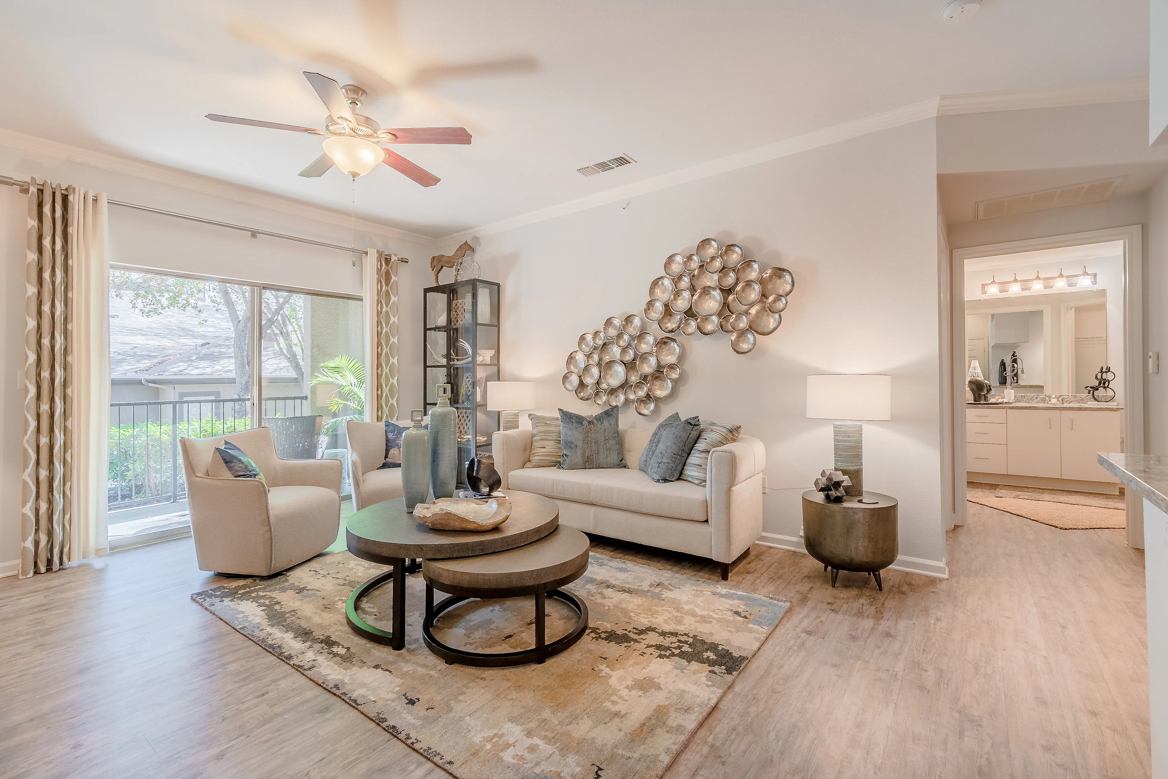 Bright, modern living room with elegant decor, plush sofa, and ambient lighting, featuring large window views of lush greenery.